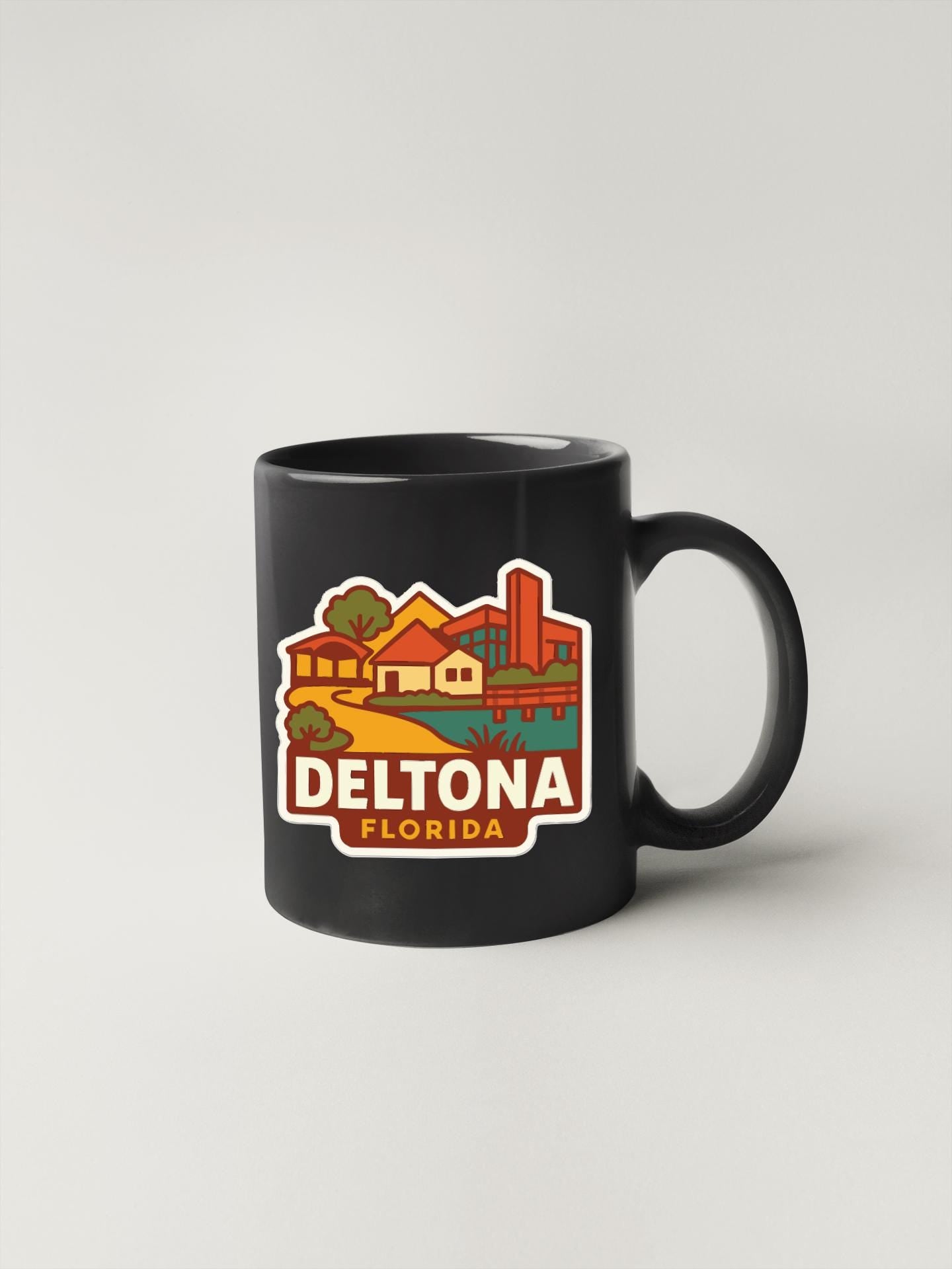 A black coffee mug with a colorful graphic depicting a cityscape and the text "DELTONA FLORIDA" printed on it.