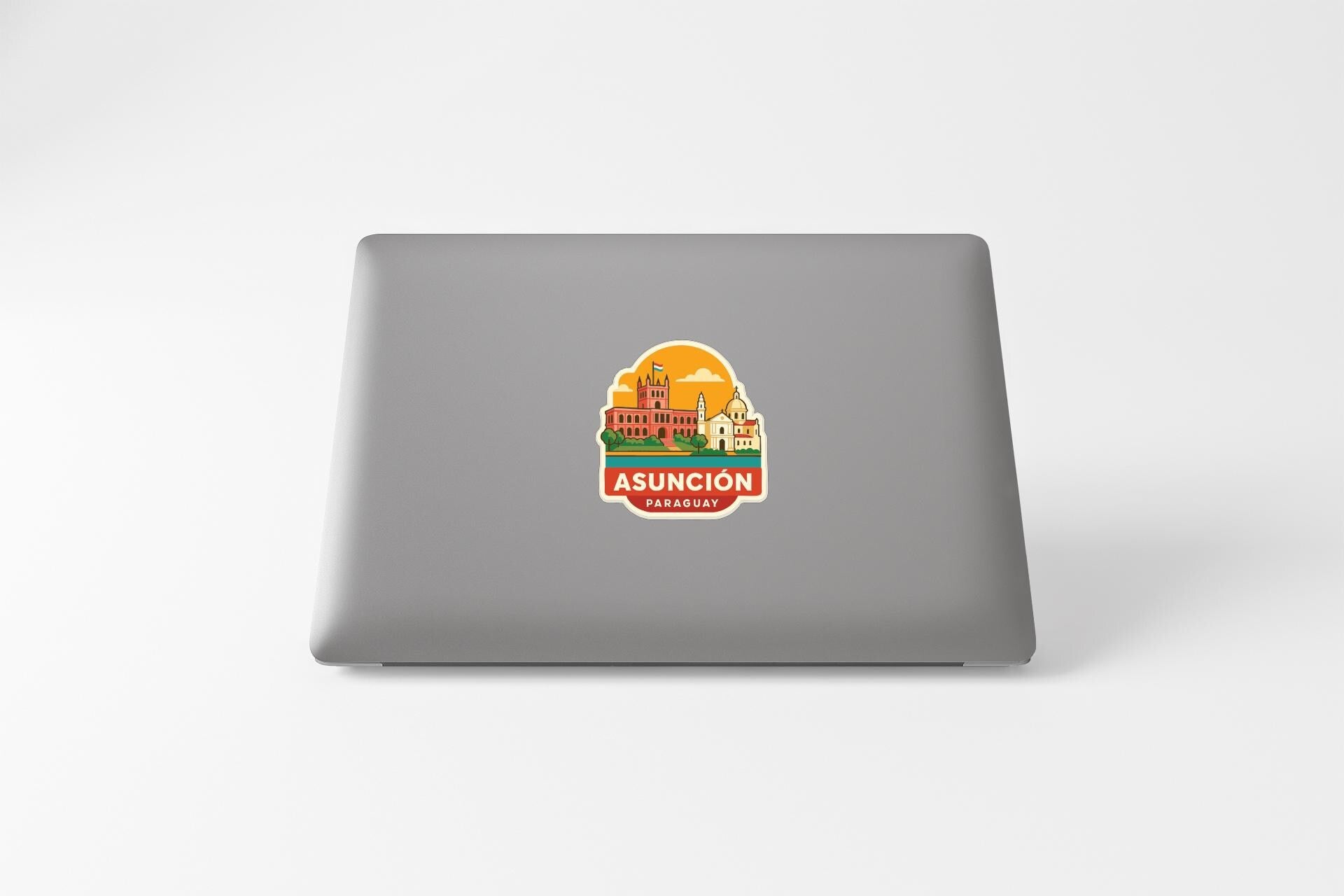 a sticker with a graphic of a building and the text "ASUNCION PAGUAY" on a laptop.