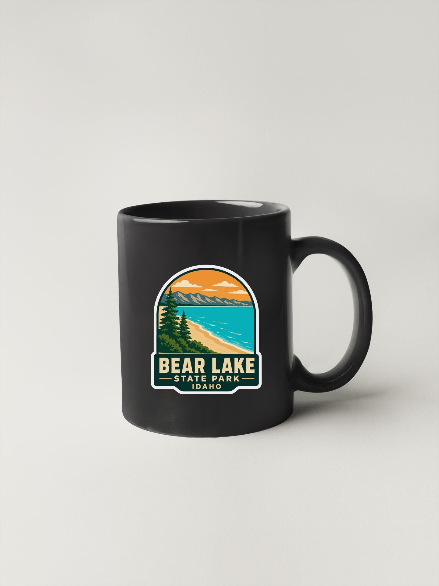 A black coffee mug with a graphic design depicting Bear Lake State Park in Idaho.