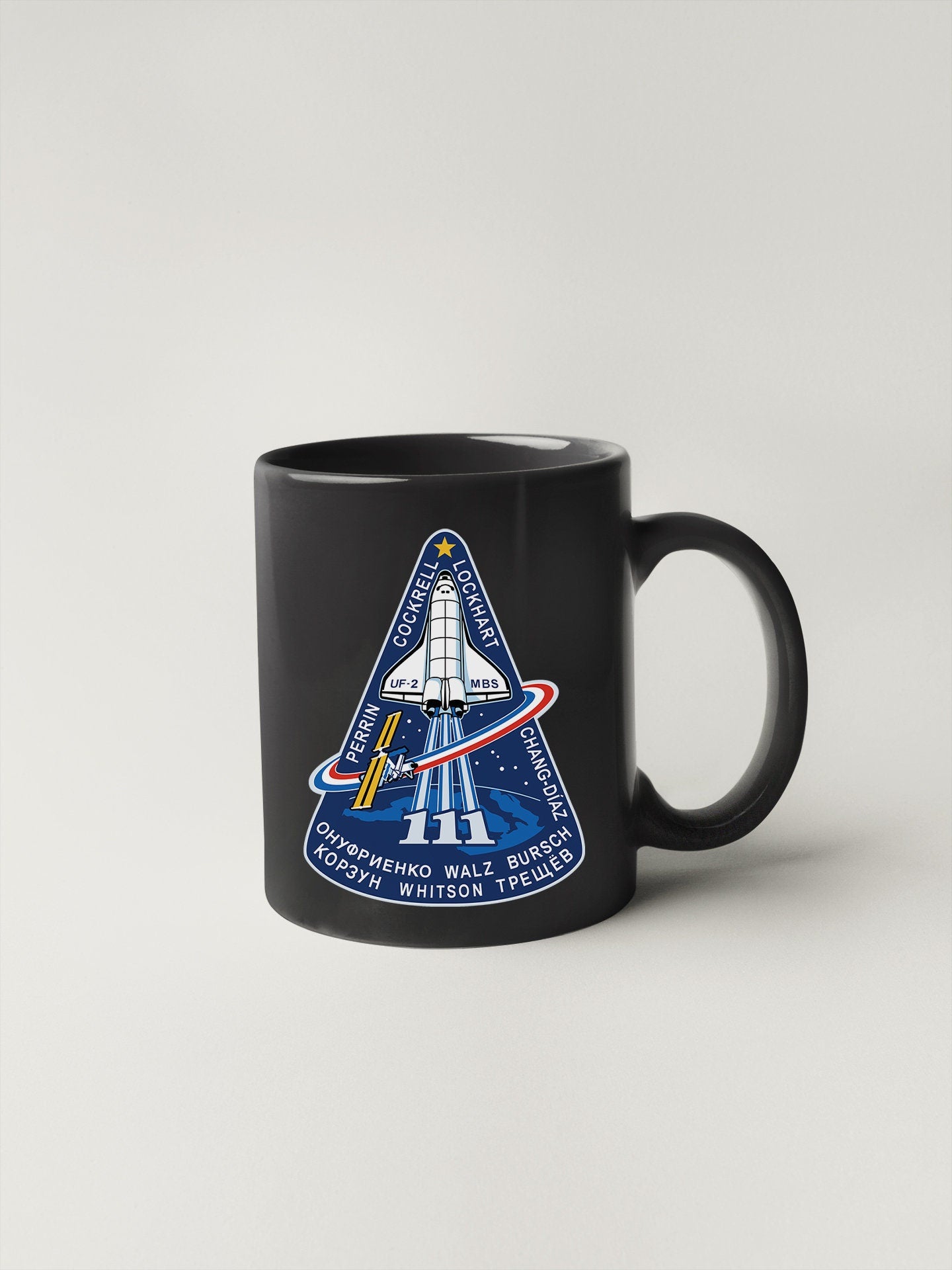 a black coffee mug with a space shuttle on it