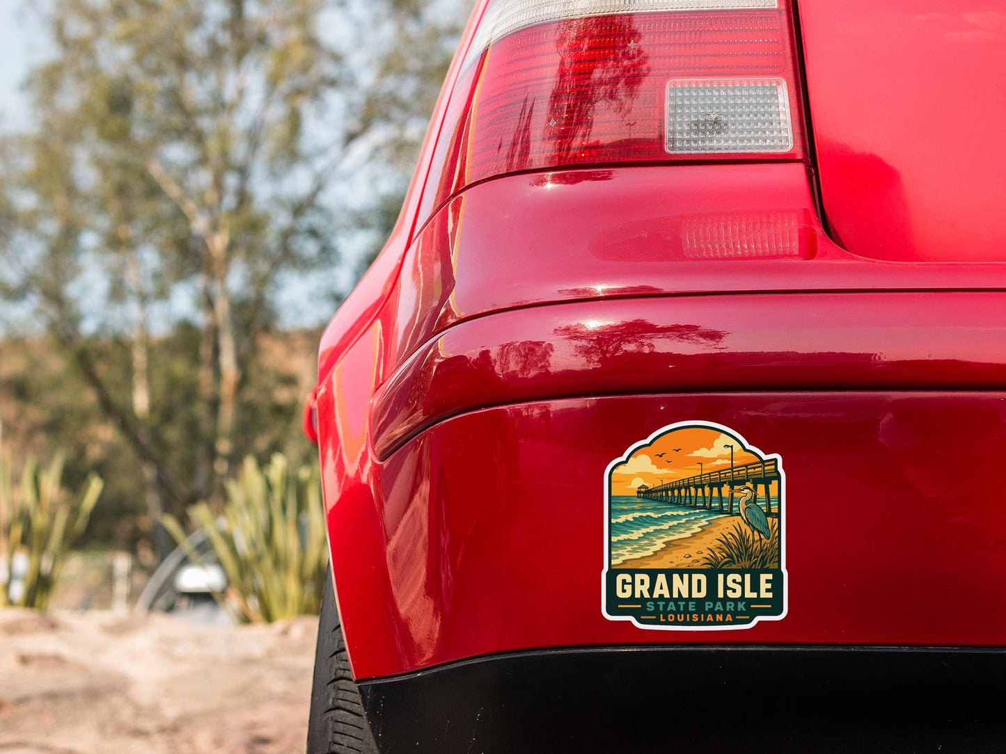 the rear end of a red car with a sticker on the trunk that says "Grand Isle State Park, Louisiana".