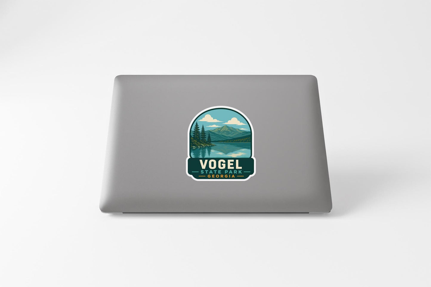 a sticker on a laptop that displays a scenic landscape with mountains, trees, and a lake.