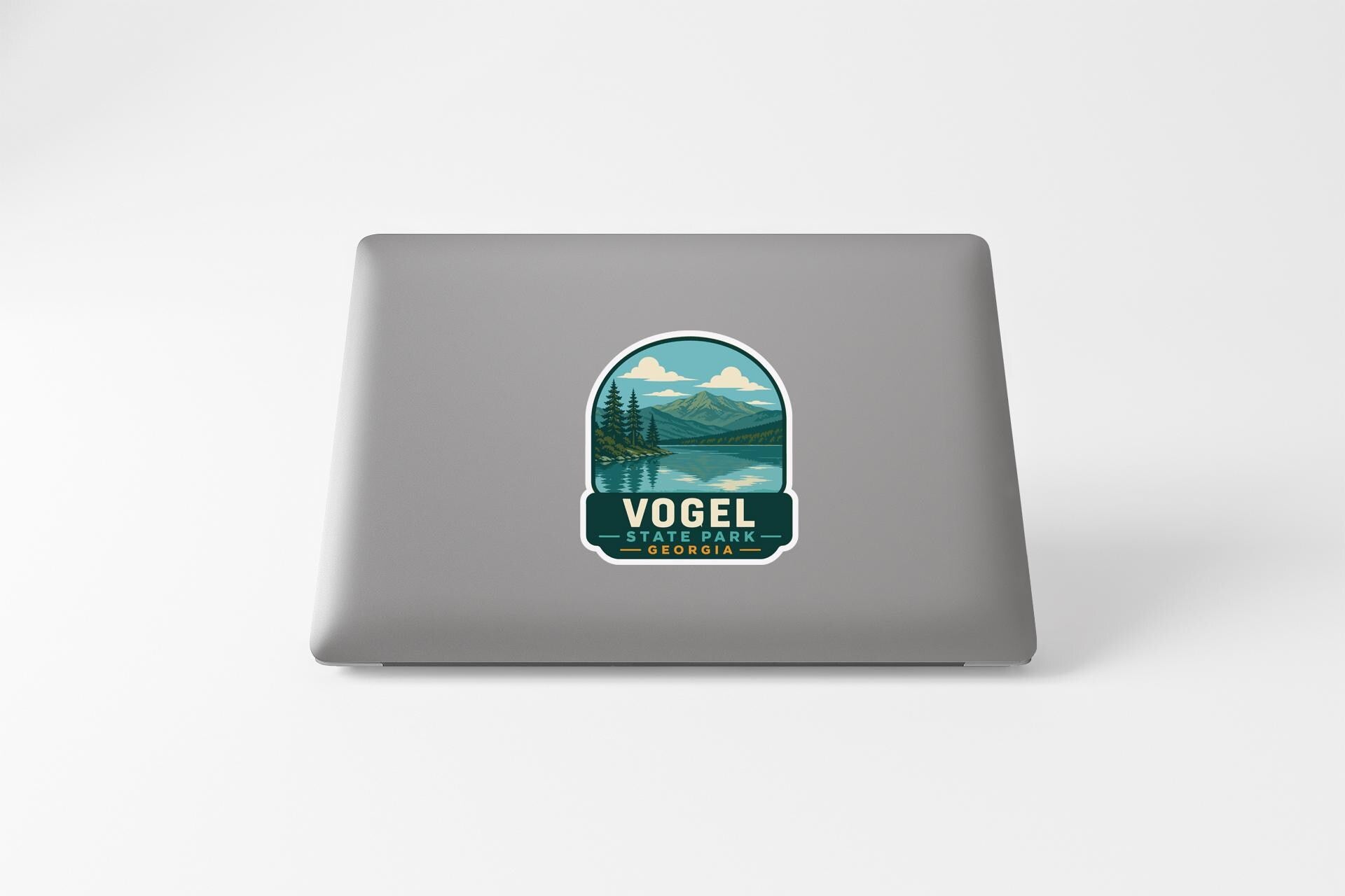 a sticker on a laptop that displays a scenic landscape with mountains, trees, and a lake.