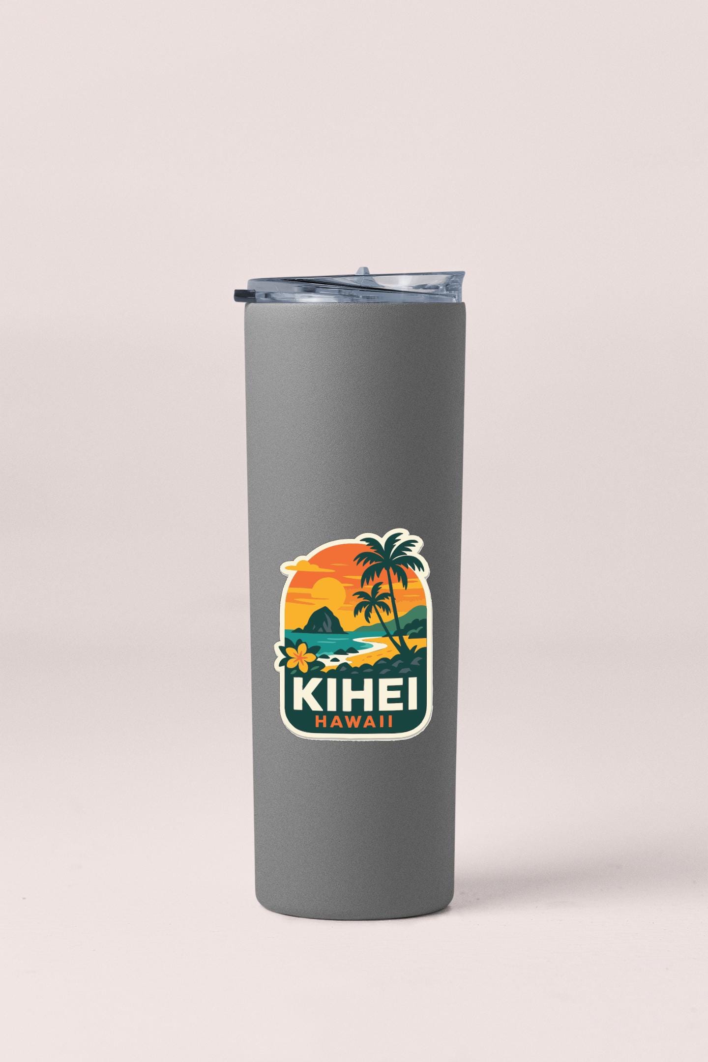 A gray insulated tumbler with a sticker depicting a tropical beach scene and palm trees.