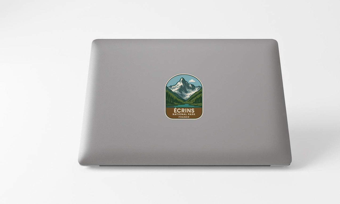A sticker with a mountain landscape and the text "ECRINS NATIONAL PARK FRANCE" is placed on the back of a laptop computer.