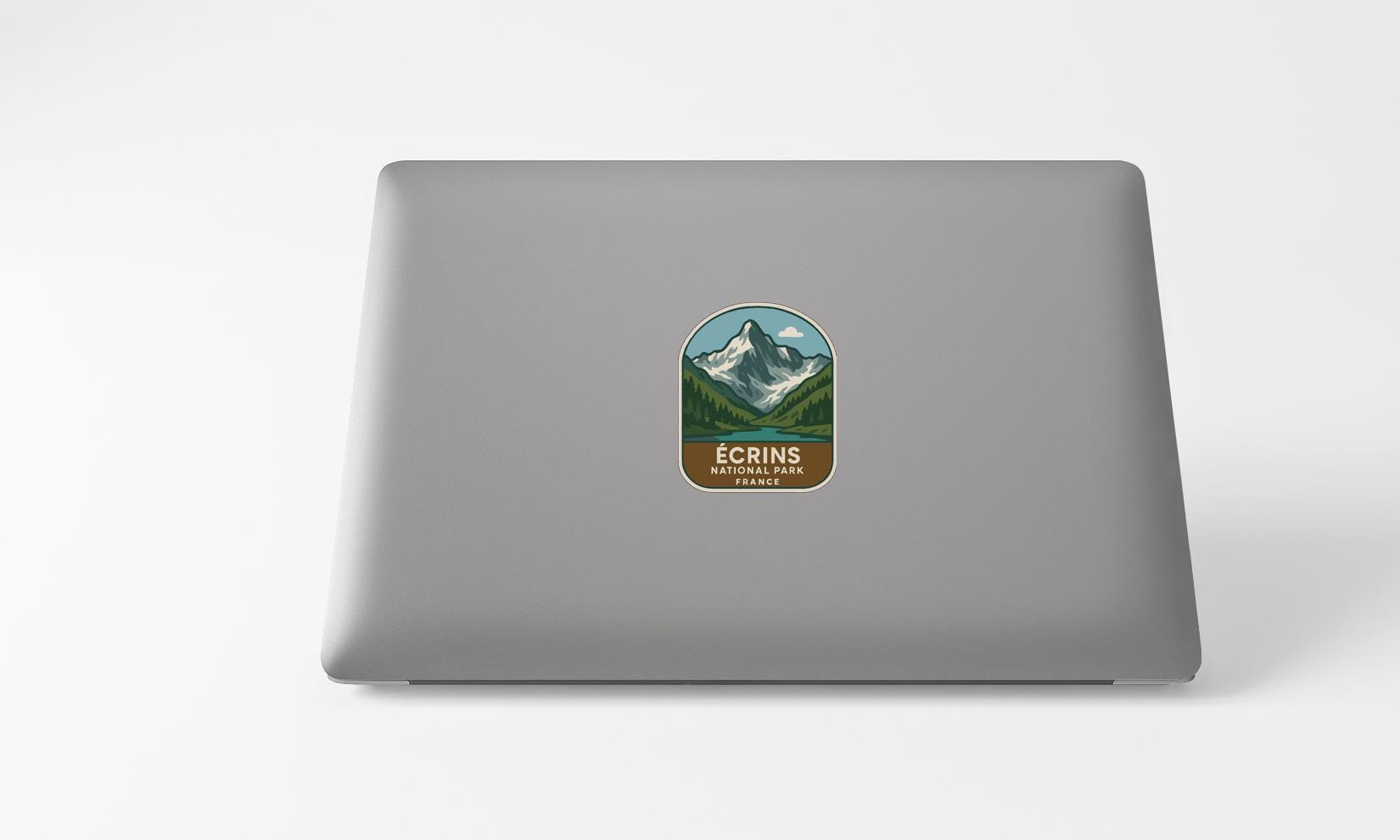 A sticker with a mountain landscape and the text "ECRINS NATIONAL PARK FRANCE" is placed on the back of a laptop computer.