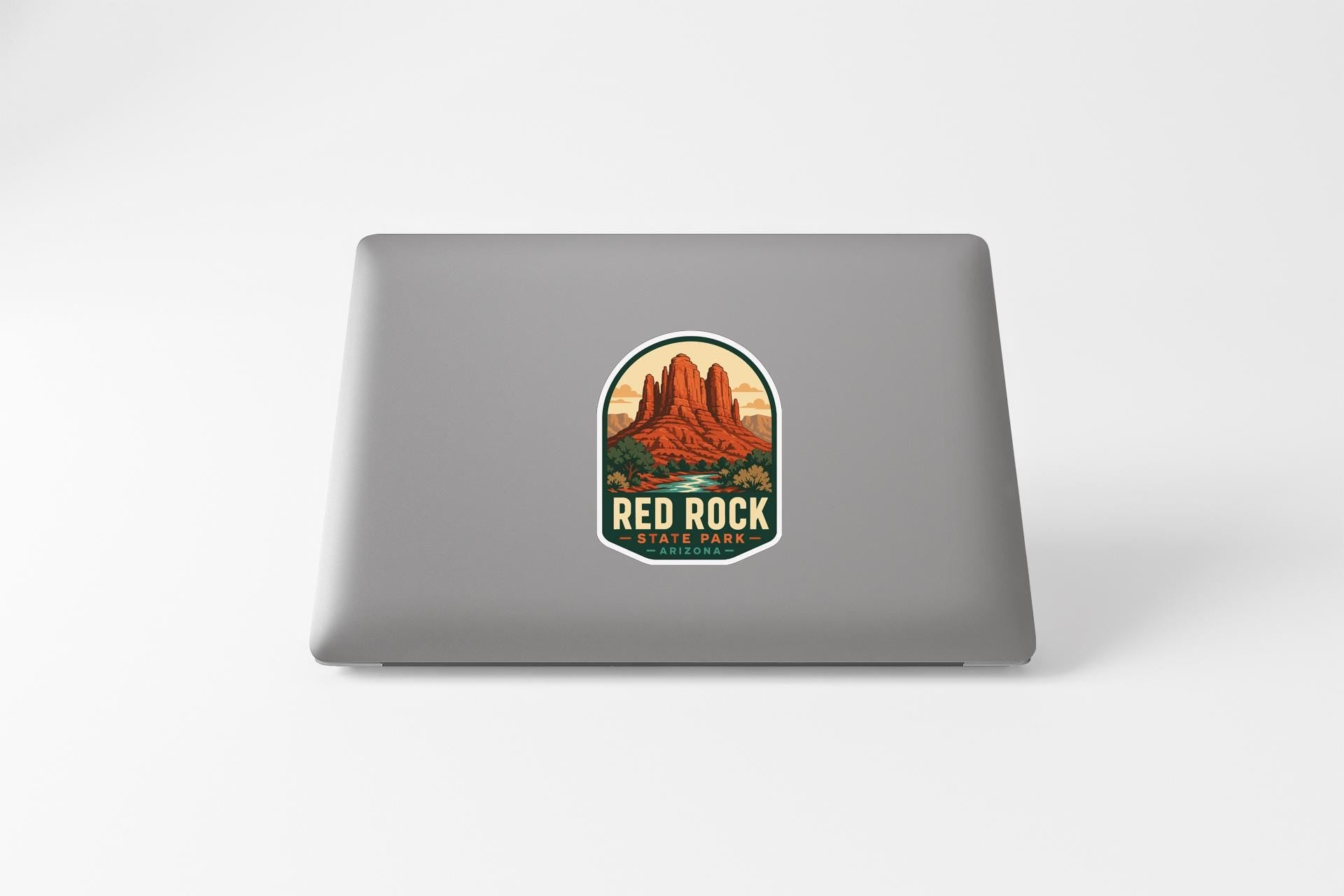 a sticker with a mountain landscape and the text "RED ROCK STATE PARK" on the back of a laptop.