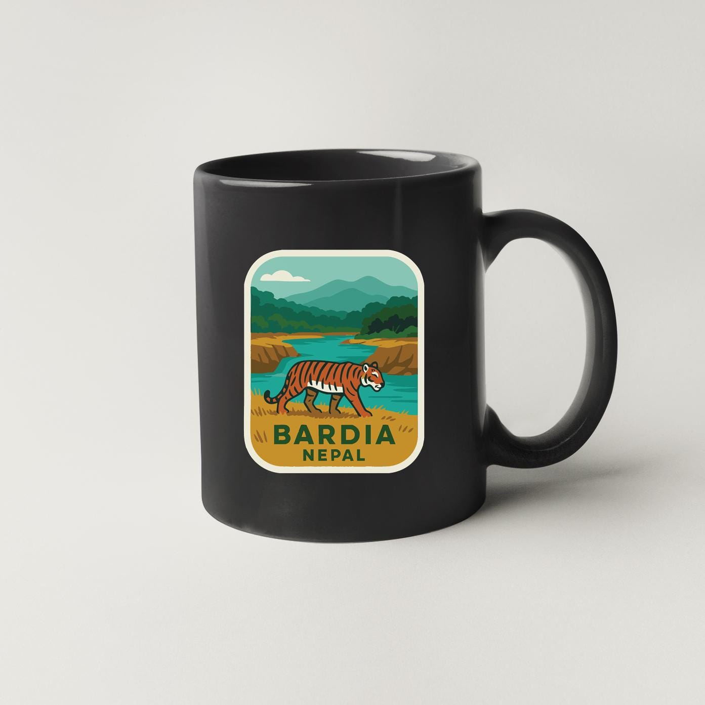 A black coffee mug with a sticker depicting a tiger walking in a natural landscape, along with the text "BARDIA NEPA".