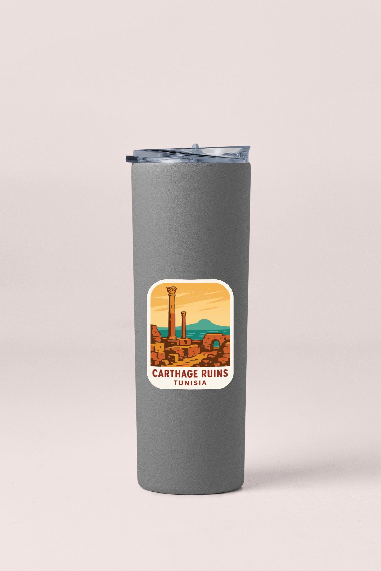 A gray insulated tumbler with a sticker depicting the Carthage Ruins in Tunisia.