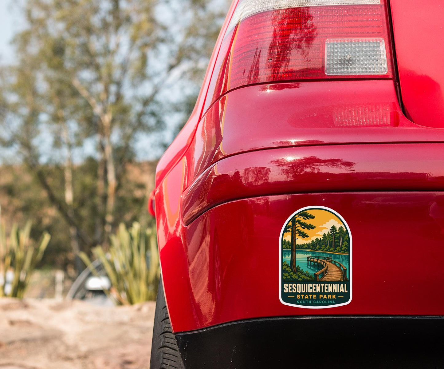 the rear end of a red car with a sticker on the back window that reads "SESQUICENTENNIAL STATE PARK SOUTH PARK".