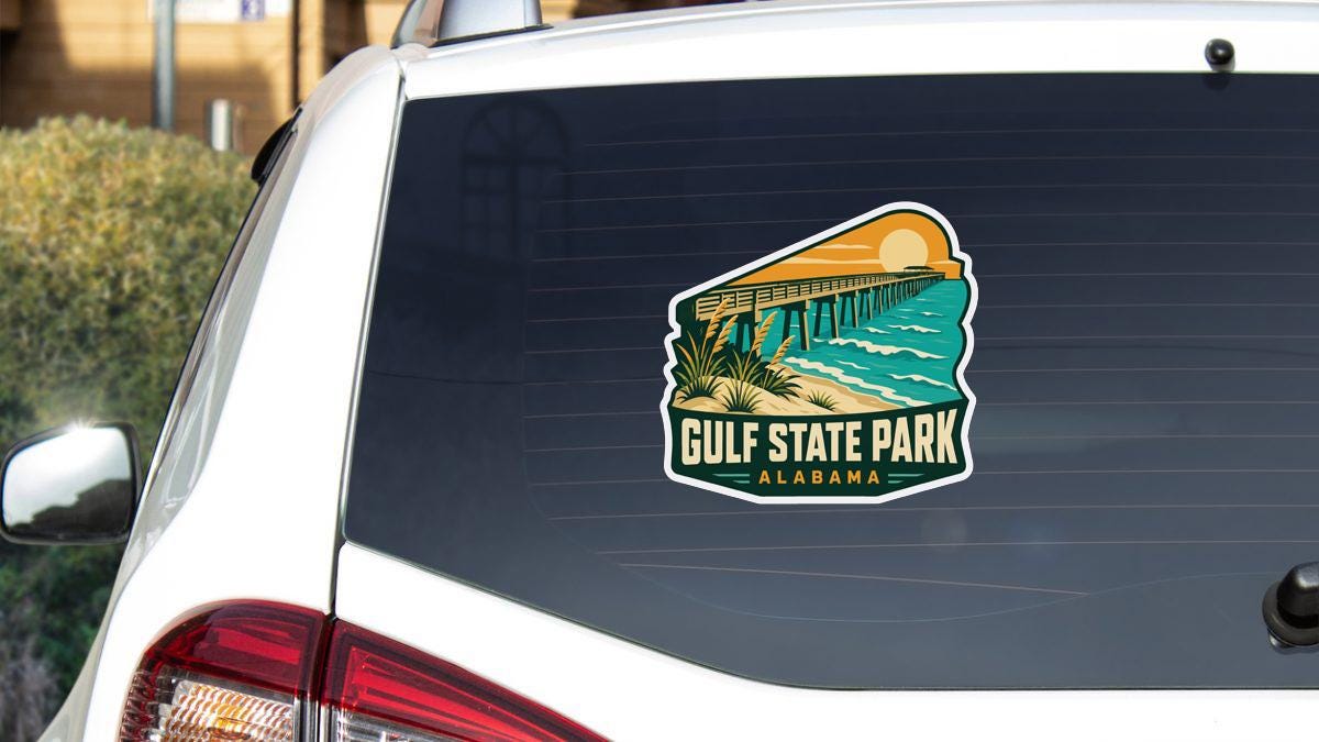 A sticker on the rear window of a white vehicle, depicting a scenic view of Gulf State Park, Alabama.