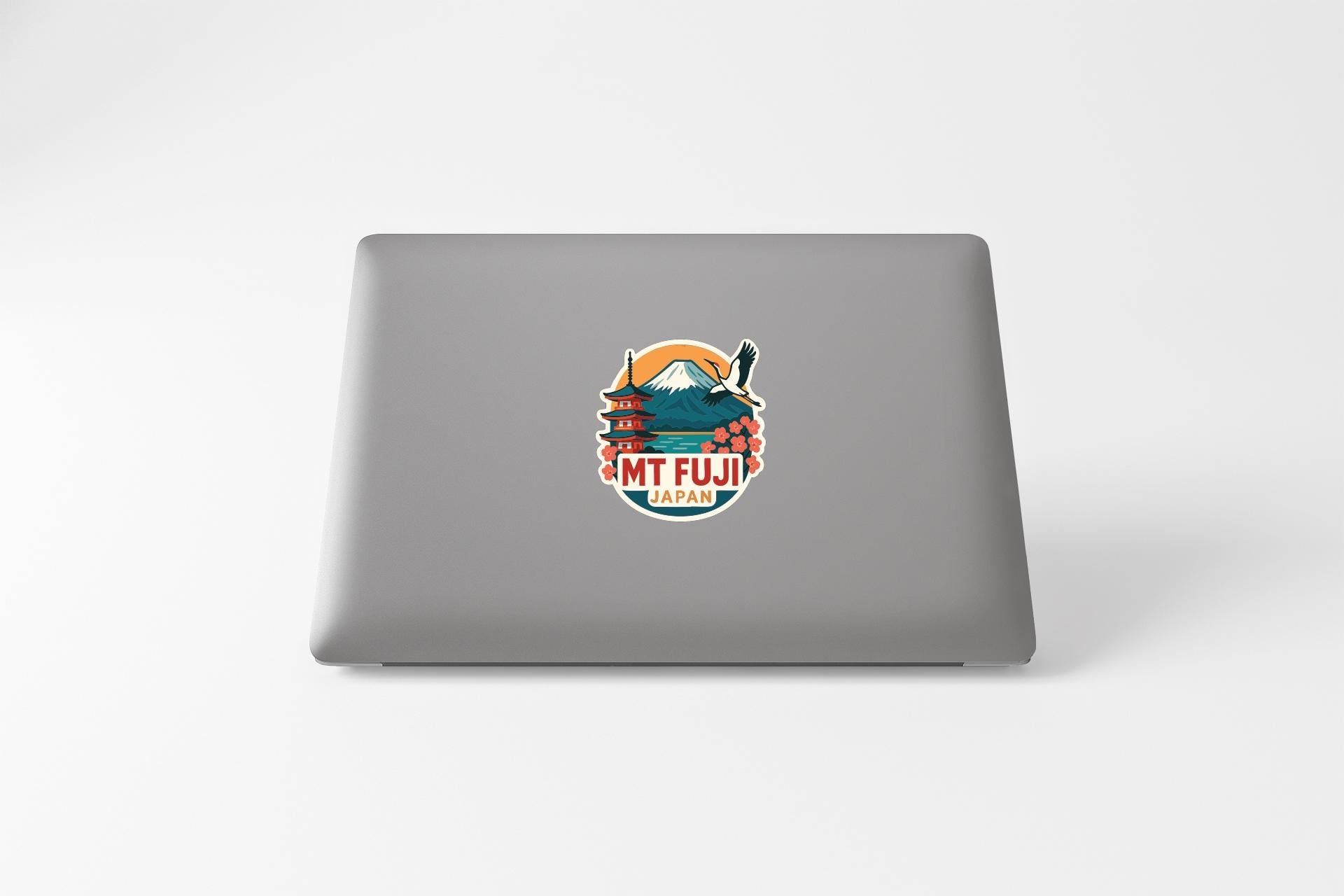 A sticker on the back of a laptop, featuring an illustration of a mountain and a temple with the text "MT fuji PAN" (mountain and temple).