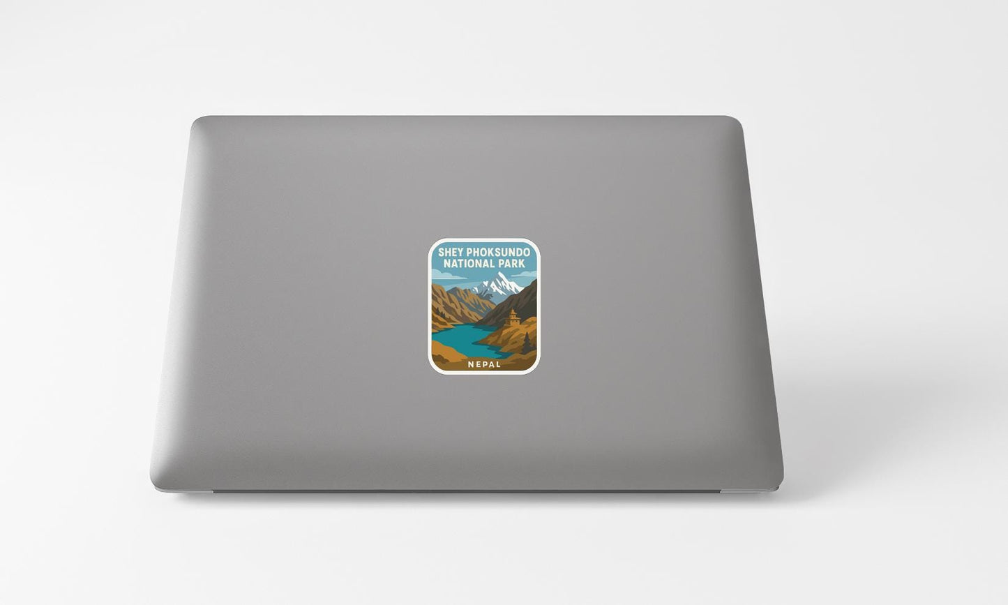 A sticker on the back of a laptop, depicting a scenic mountain landscape with a river.