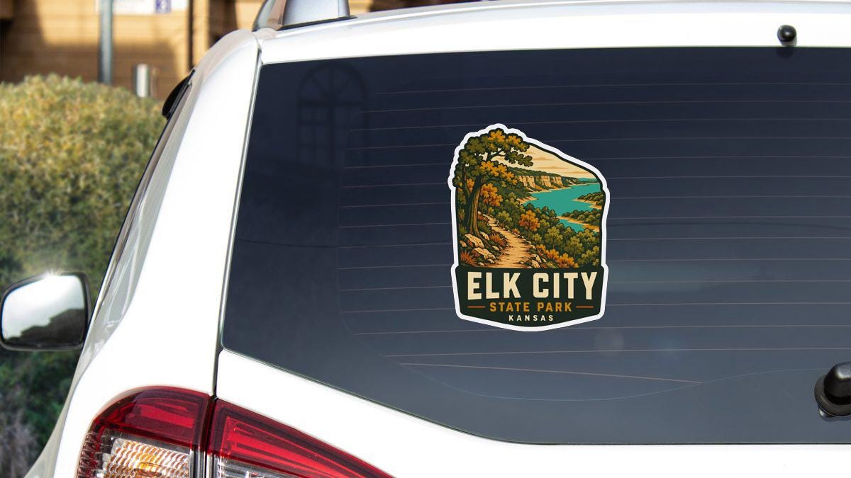 A sticker on the rear window of a white car, depicting a scenic landscape with a path leading to a lake.