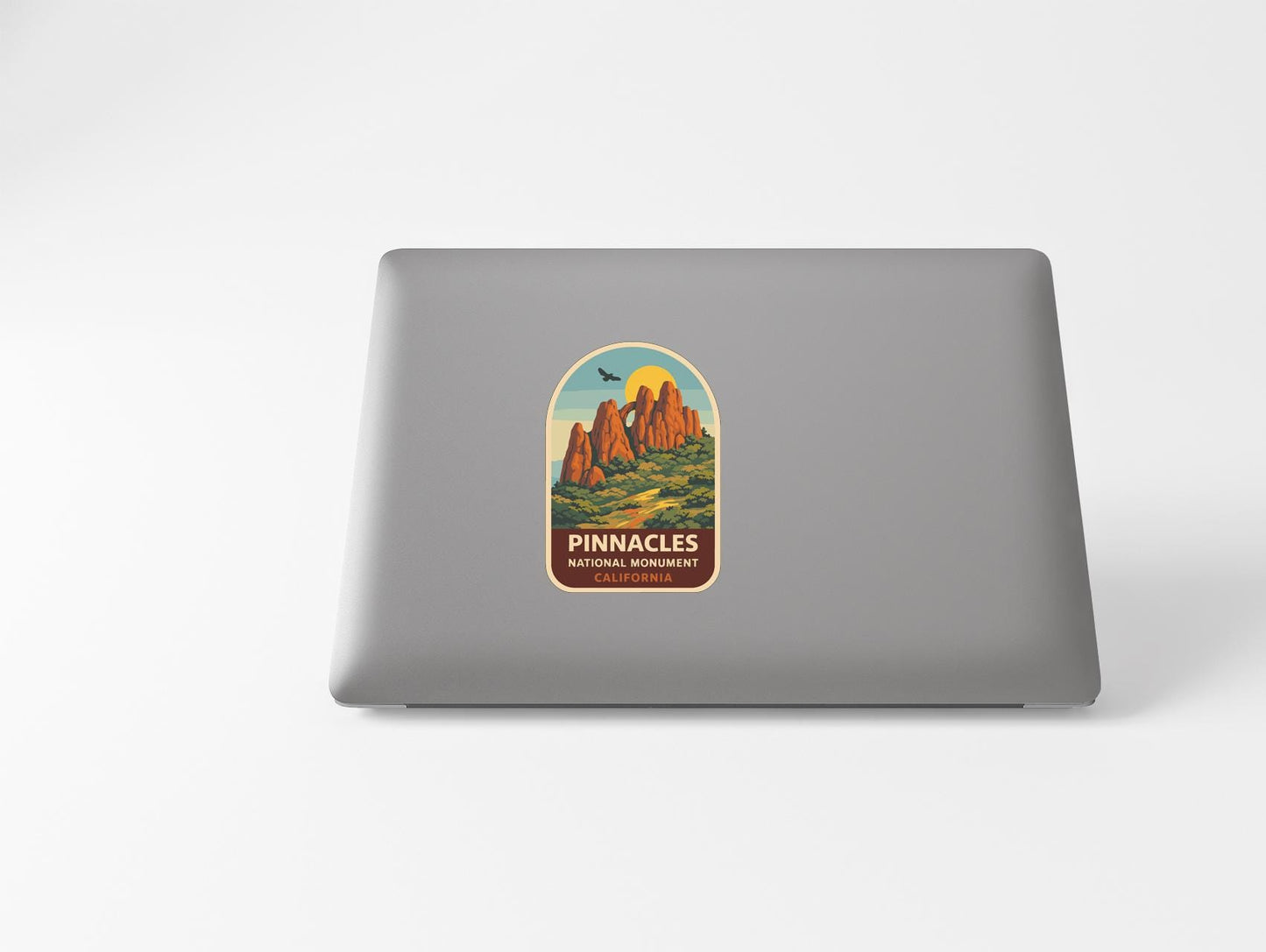 A sticker on the back of a laptop, depicting a scenic landscape with mountains and a bird in flight.