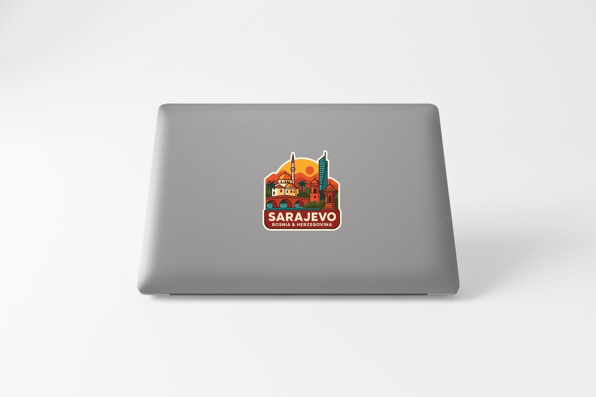 a sticker on the back of a laptop with an illustration of a cityscape and the text "SARAJEVO BOMBAHNIA HERRERA".
