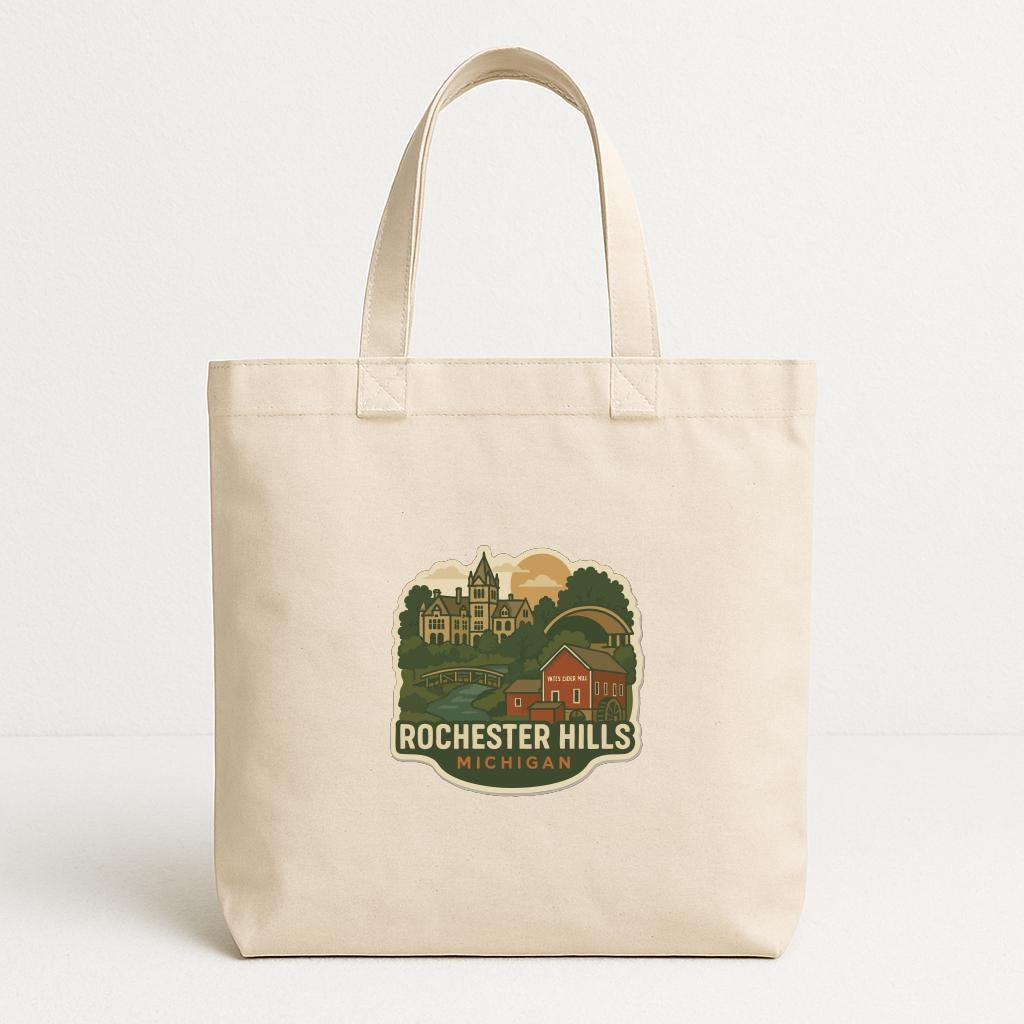A beige tote bag with a graphic design featuring a scenic view of Rochester Hills, Michigan.