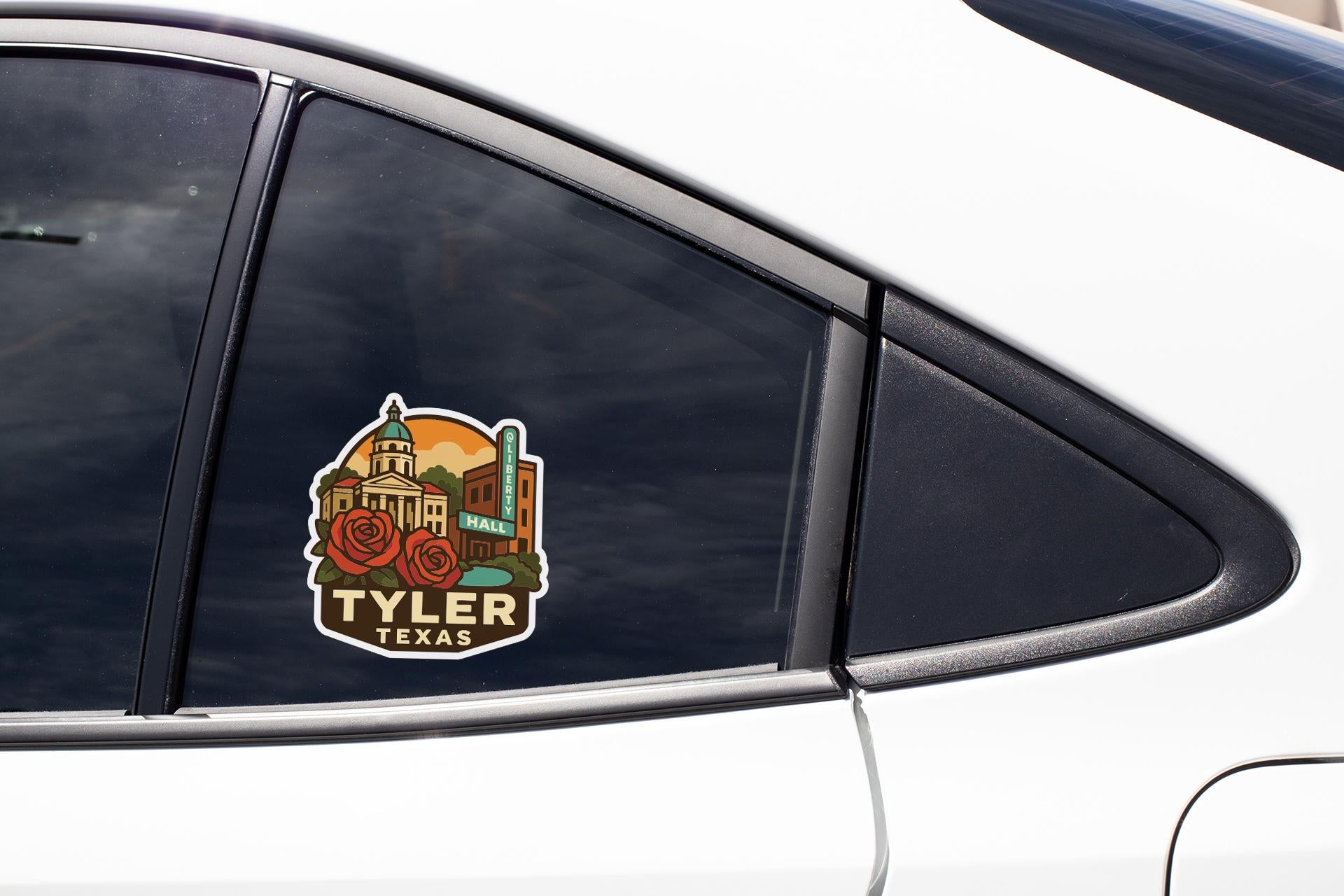 A sticker on the side of a car window, featuring a colorful illustration of a city skyline with a prominent building labeled " Tyler, Texas".