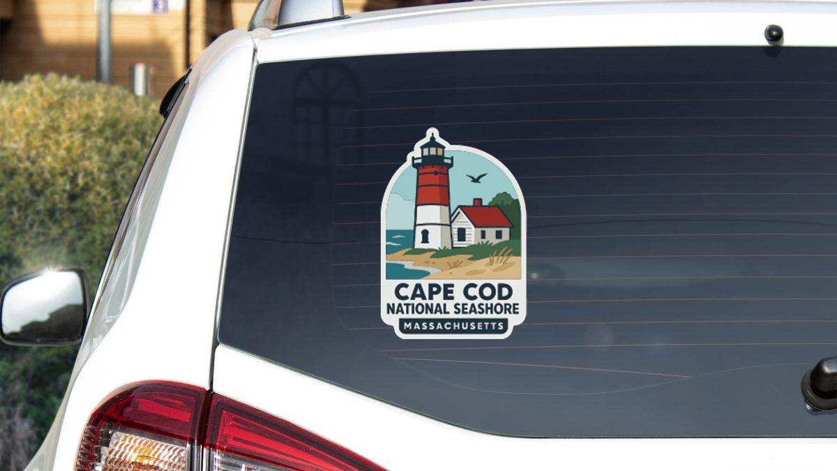 a sticker on the rear window of a vehicle, depicting a lighthouse and the text "Cape Cod National Seashore Massachusetts".