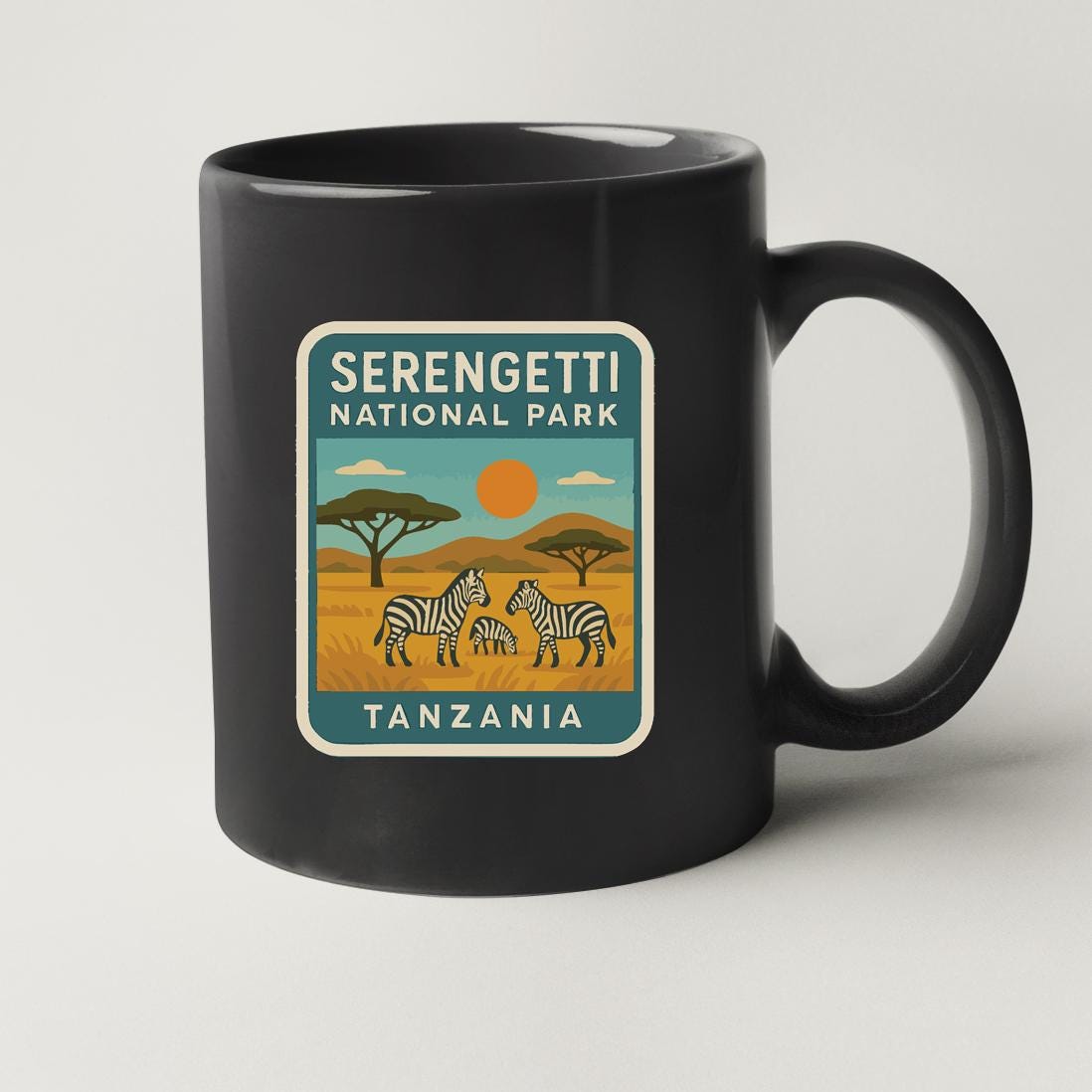 A black coffee mug with a label that says "Serengeti National Park Tanzania".