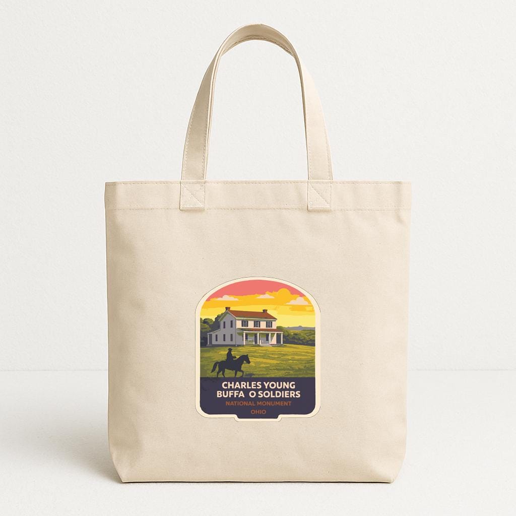 A beige tote bag with a graphic design depicting a house and a person riding a horse, along with text that reads "Charles Young Buffa O Soldiers".