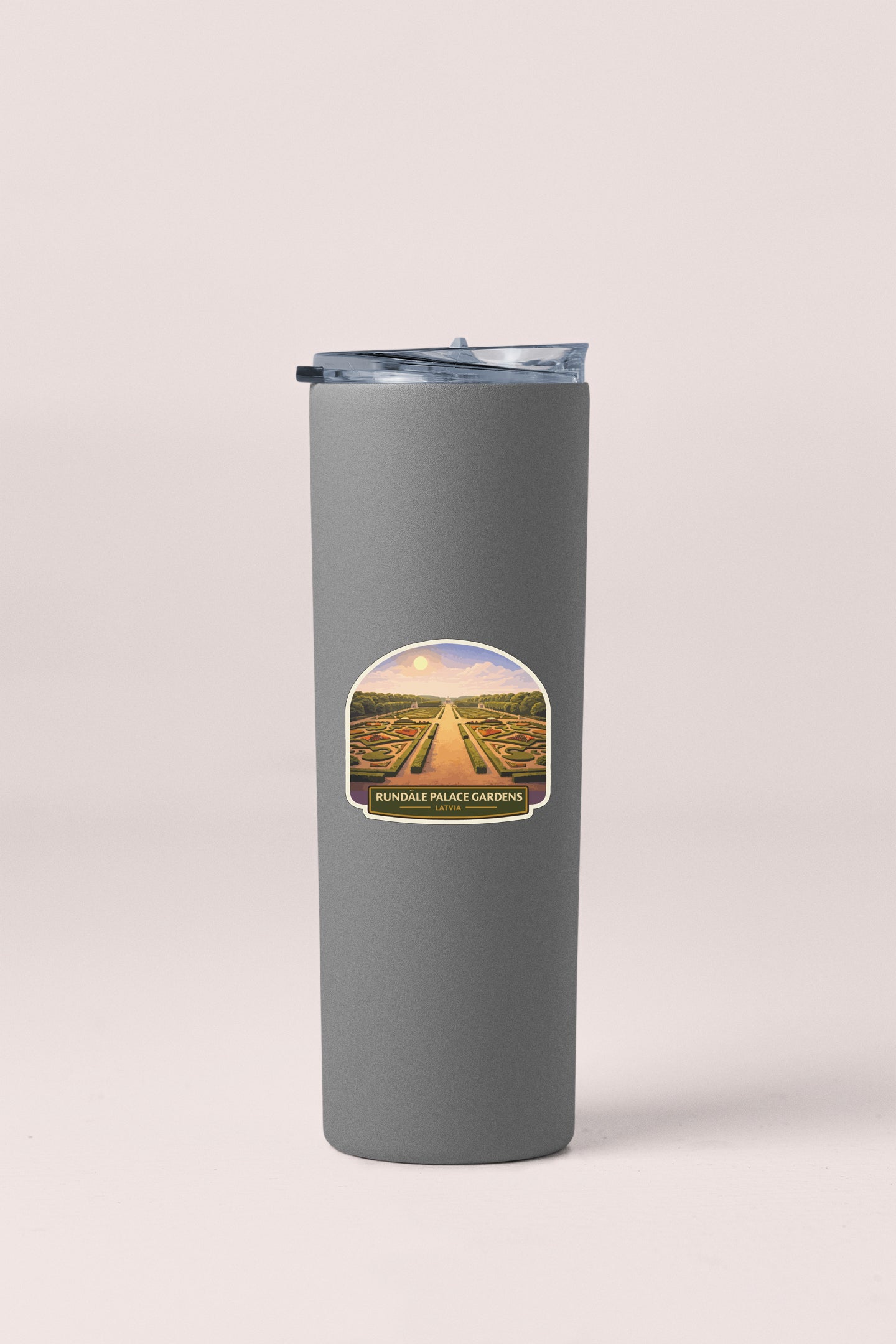 A gray insulated tumbler with a label depicting a scenic view of a garden.