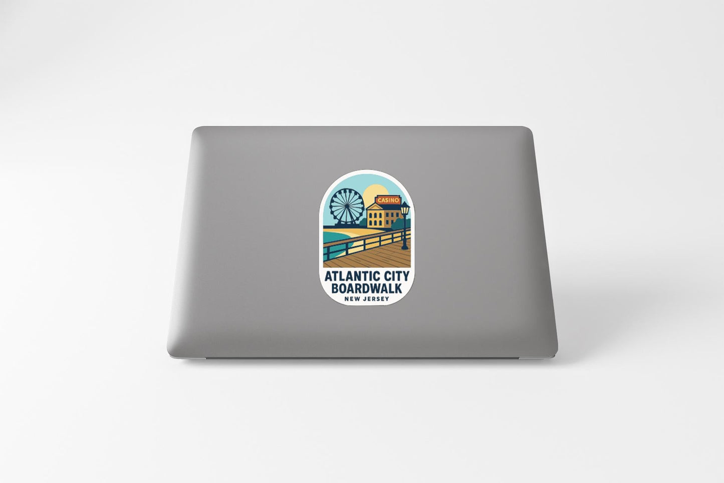 a sticker on the back of a laptop that displays an illustration of a boardwalk and a ferris wheel, along with the text "ATLANTIC CITY BOARDWALK NEW JERSEY".