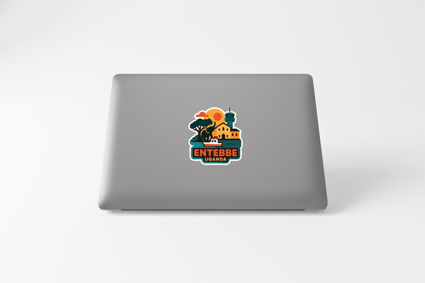 a sticker on the back of a laptop with a colorful illustration of a cityscape and the text "ENTEBBE UBANDA" printed on it.