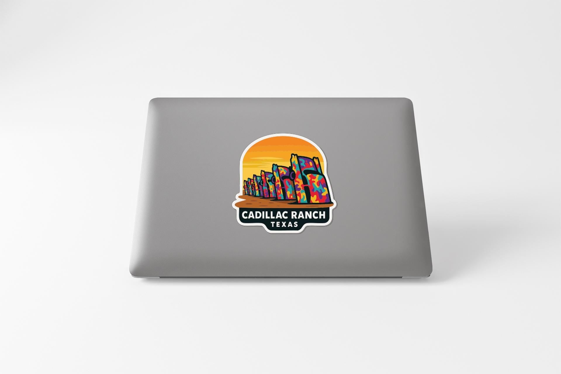 A sticker on the back of a laptop, depicting a sunset over a city skyline with the text "Cadillac Ranch, Texas" below it.