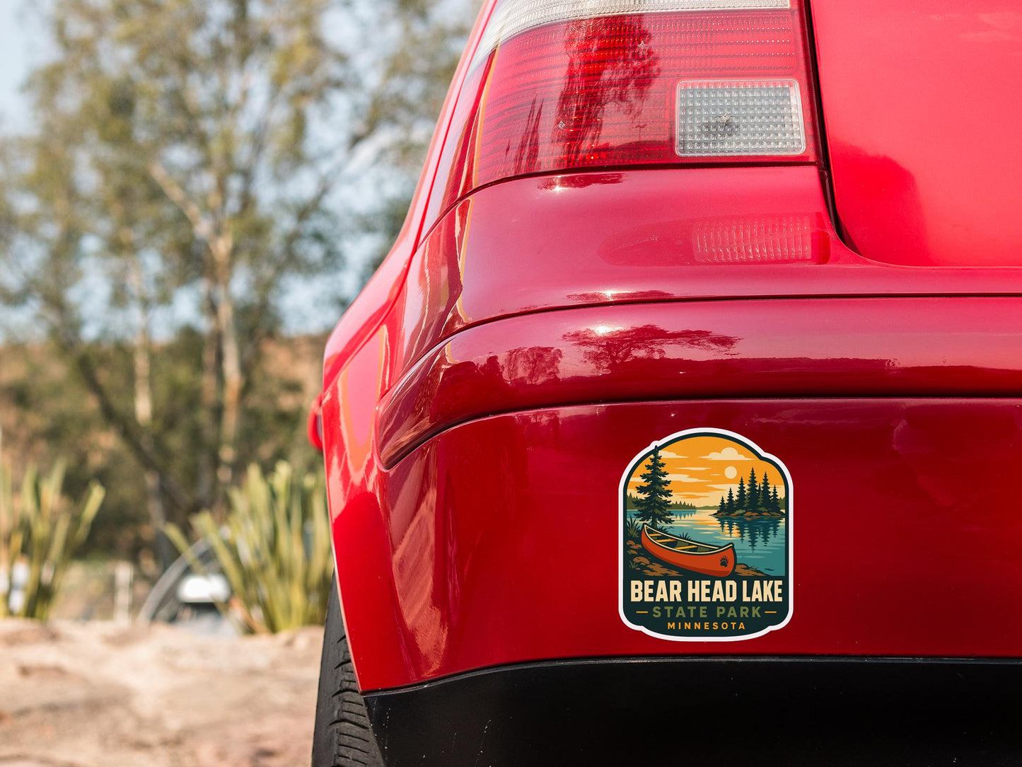 the rear end of a red car with a sticker on the trunk that reads "BEAR HEAD LAKE STATE PARK MINNESOTA".