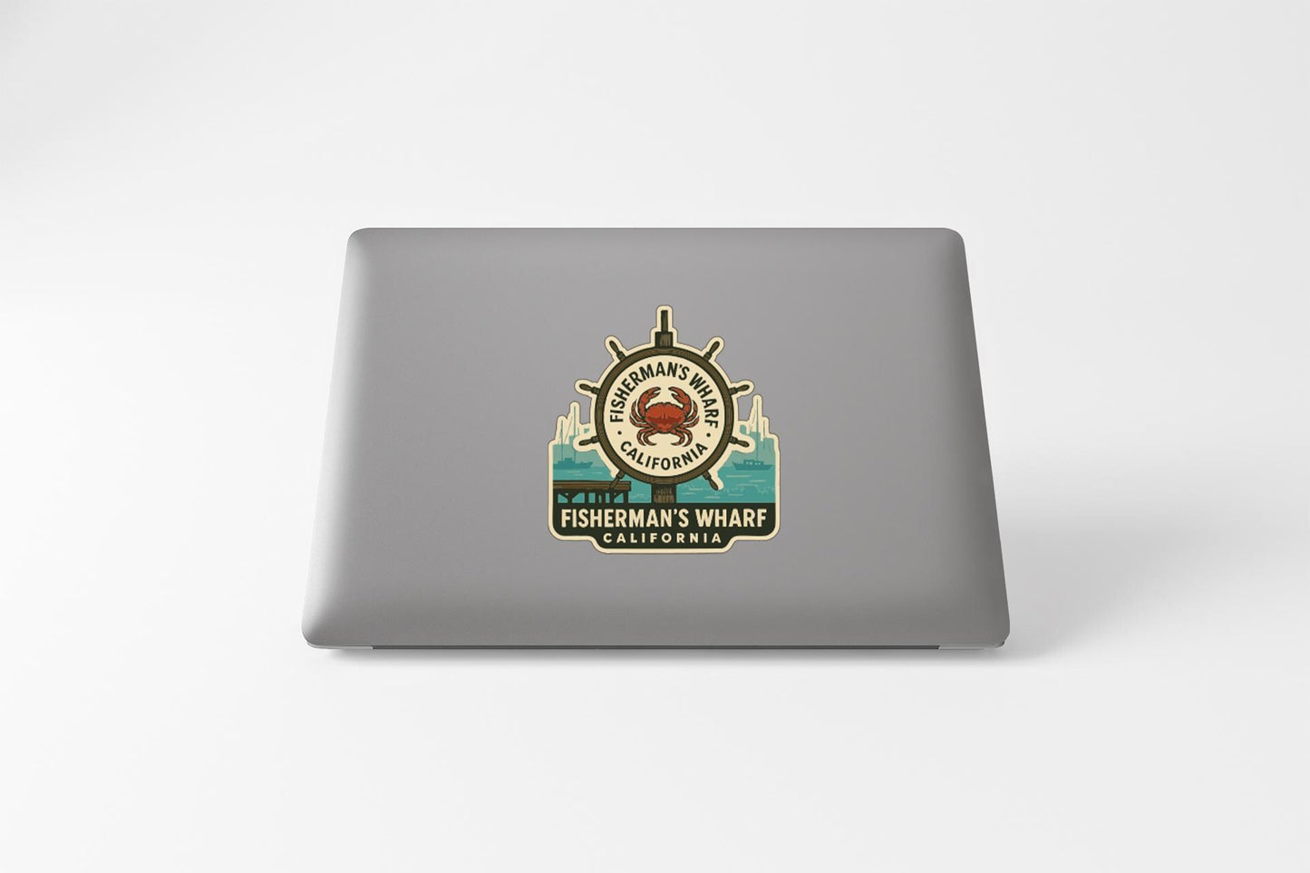 a sticker on the back of a laptop, depicting a lighthouse and a crab, with the text "FISHERMAN'S WHARF CALIFORNIA" printed on it.