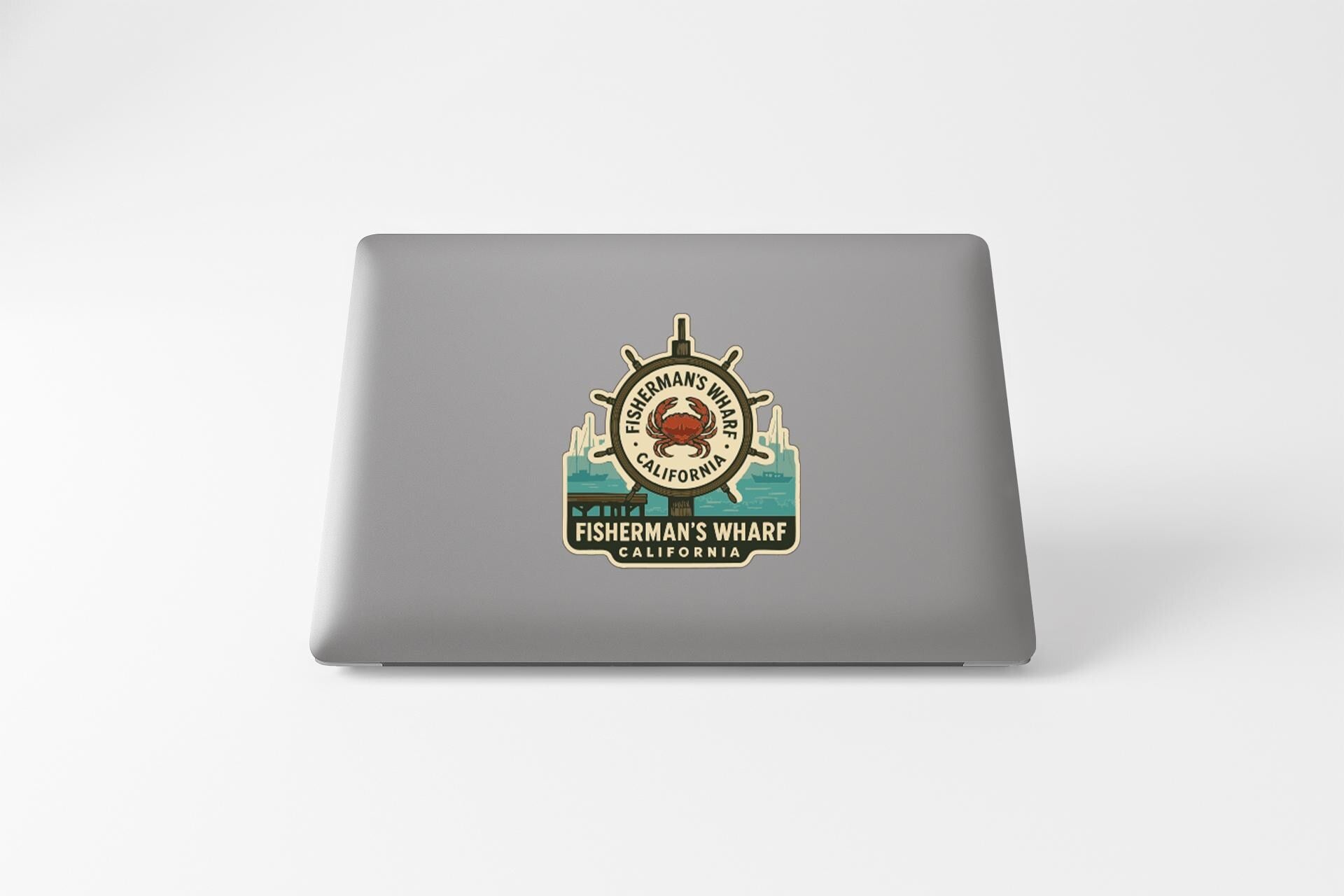 a sticker on the back of a laptop, depicting a lighthouse and a crab, with the text "FISHERMAN'S WHARF CALIFORNIA" printed on it.