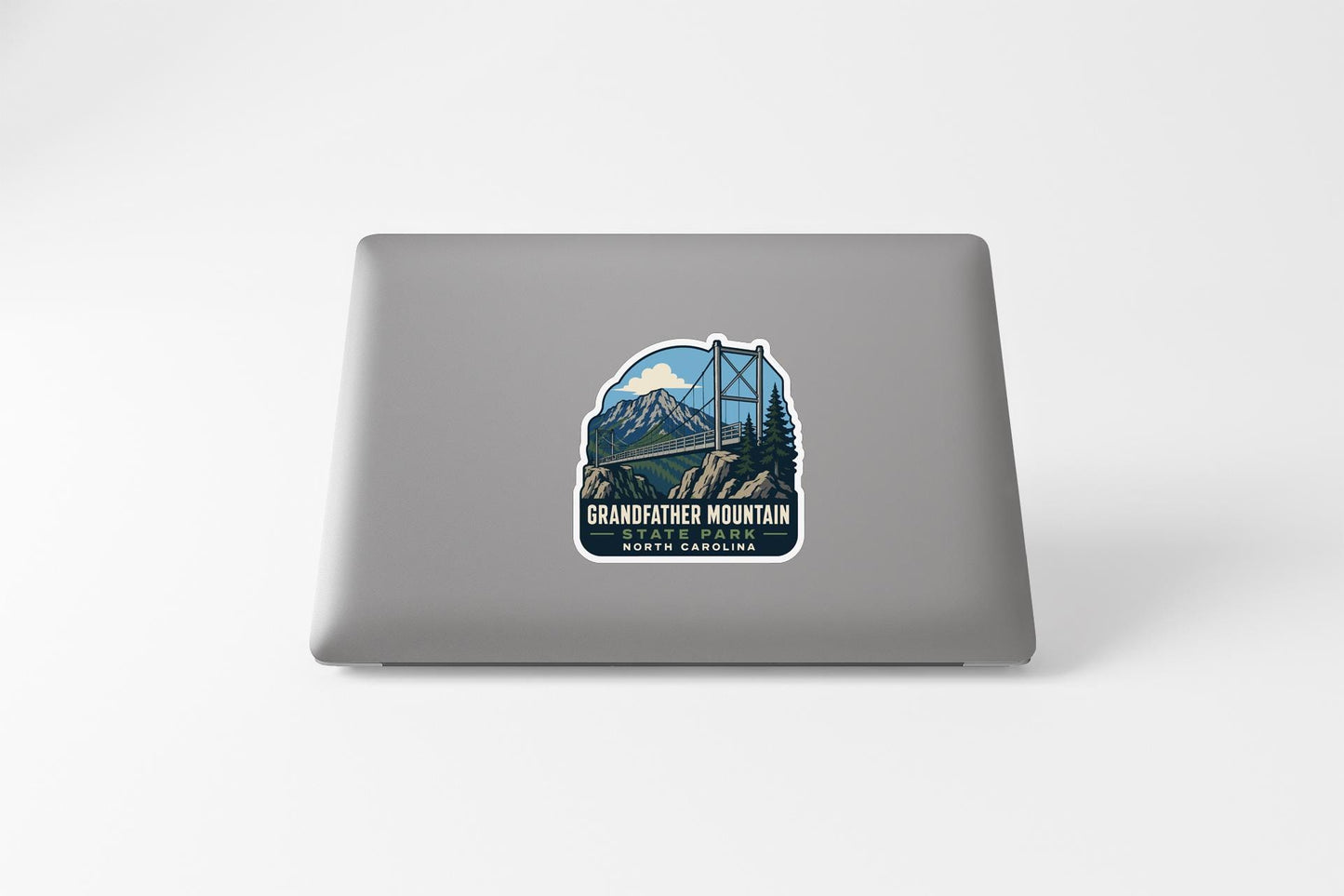 A sticker on the back of a laptop, depicting a bridge over a mountain with a scenic landscape.