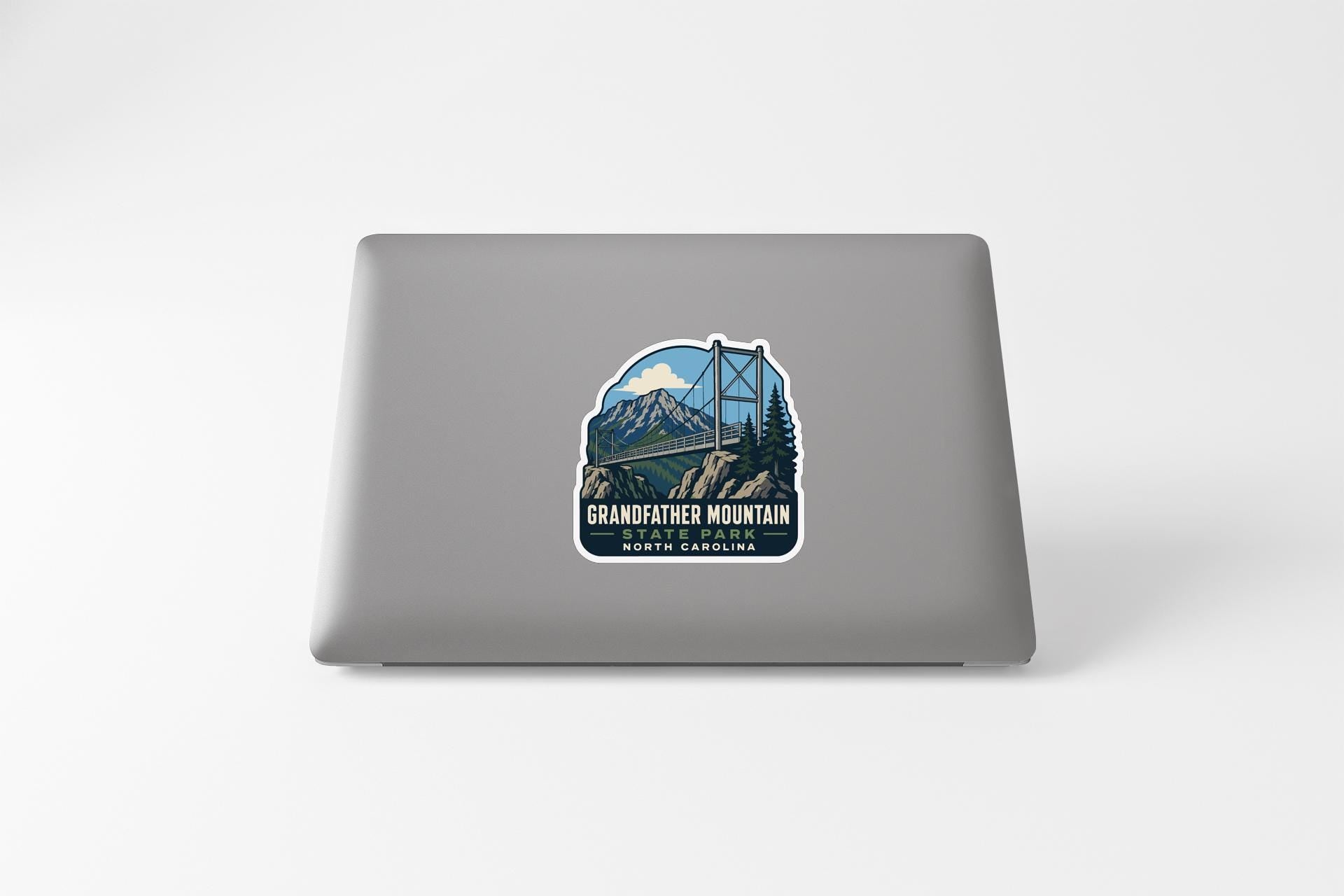 A sticker on the back of a laptop, depicting a bridge over a mountain with a scenic landscape.