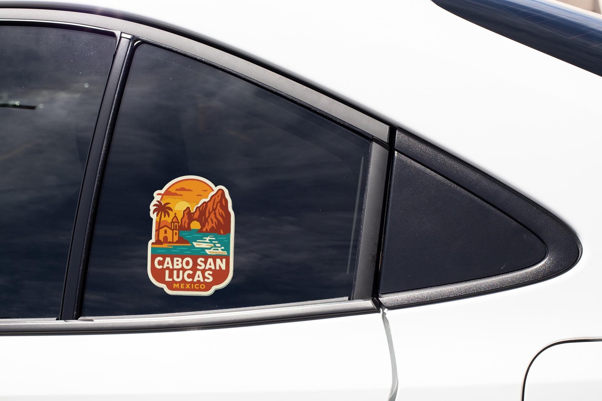A sticker on the side of a car window, depicting a scenic landscape with mountains, palm trees, and a sunset.