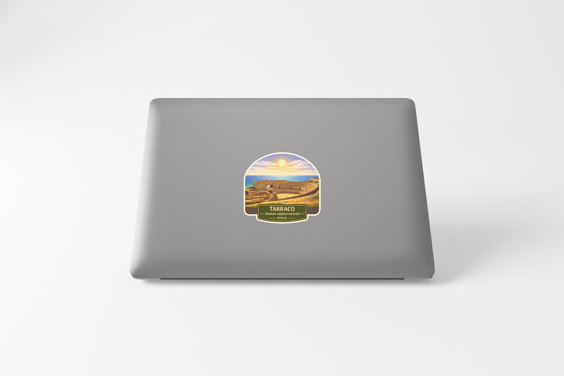 a sticker on the back of a laptop, depicting a scenic landscape with a mountain range and a sunset.