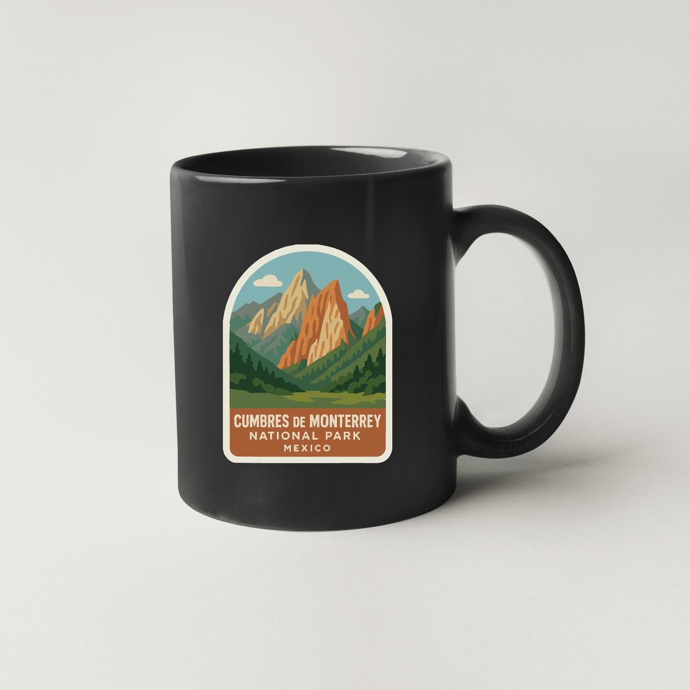A black coffee mug with a label that says "Cumbres de Monterey National Park Mexico".