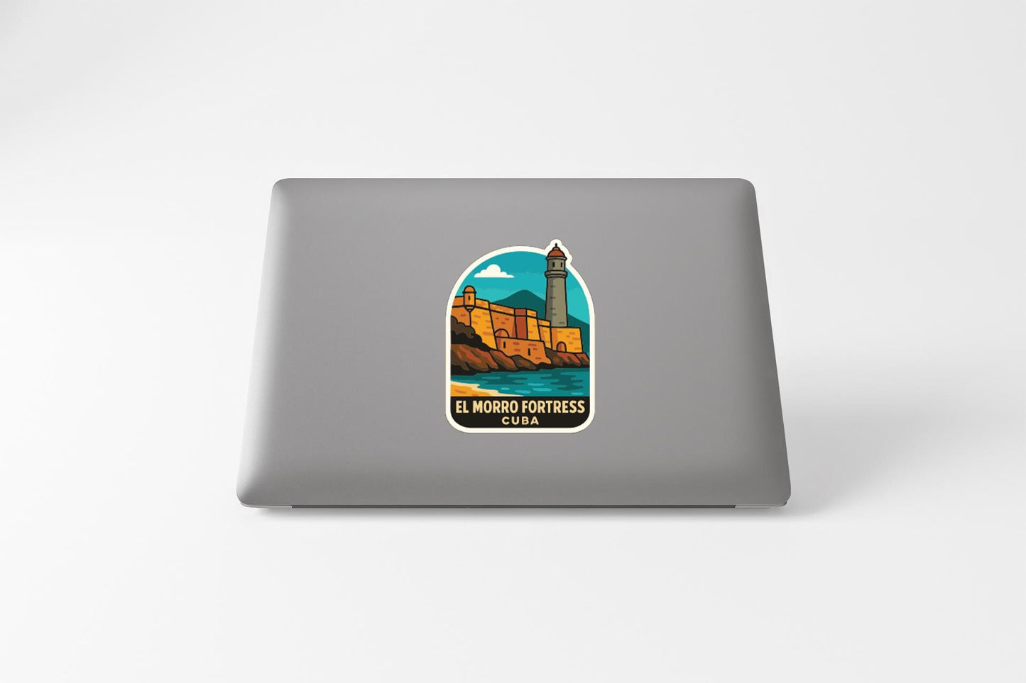 A sticker on the back of a laptop, depicting a lighthouse and a castle, with the text "EL MONRO FORTRECE CUBA" printed on it.
