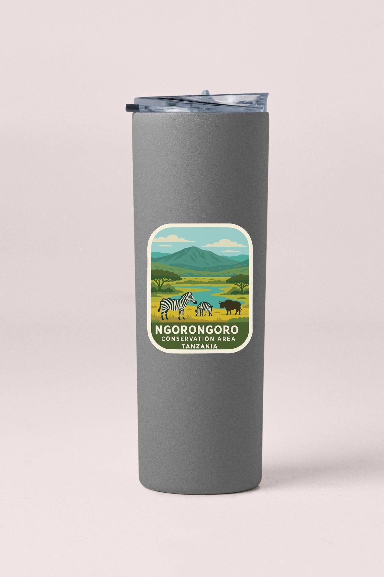 A gray tumbler with a label that features an illustration of wildlife in a natural setting, along with the text "NGORONGOORO CONSERVATION AREA TANZANIA".