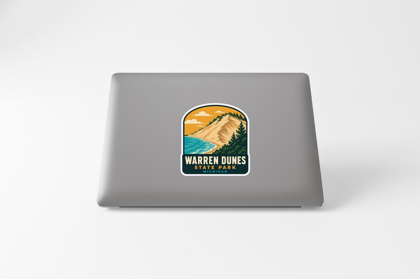 A sticker featuring a mountain landscape with a beach and ocean, along with the text "WARREN DUNES STATE PARK".