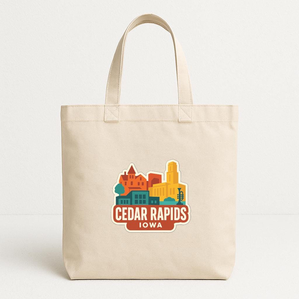 A beige tote bag with a colorful graphic of a city skyline and the text "Cedar Rapids Iowa" printed on it.