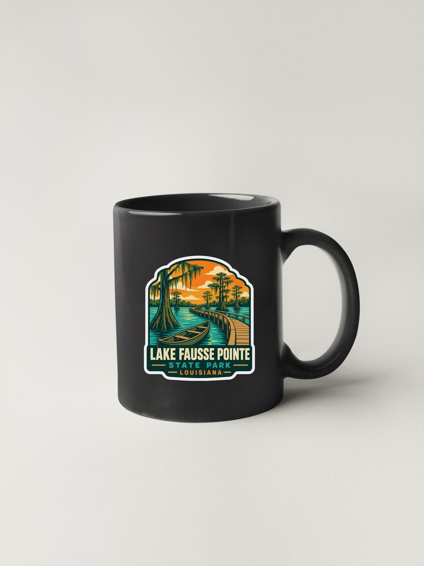A black coffee mug with a colorful illustration of a tropical landscape, including palm trees, a river, and a sunset.