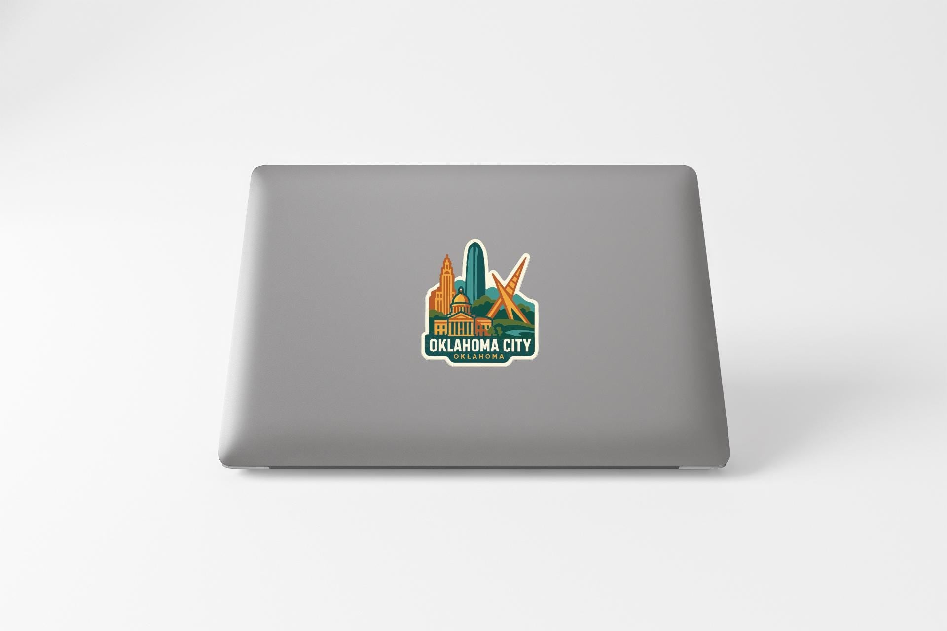 a sticker on the back of a laptop that displays the text "OKLAHOMA CITY" along with an illustration of a city skyline.