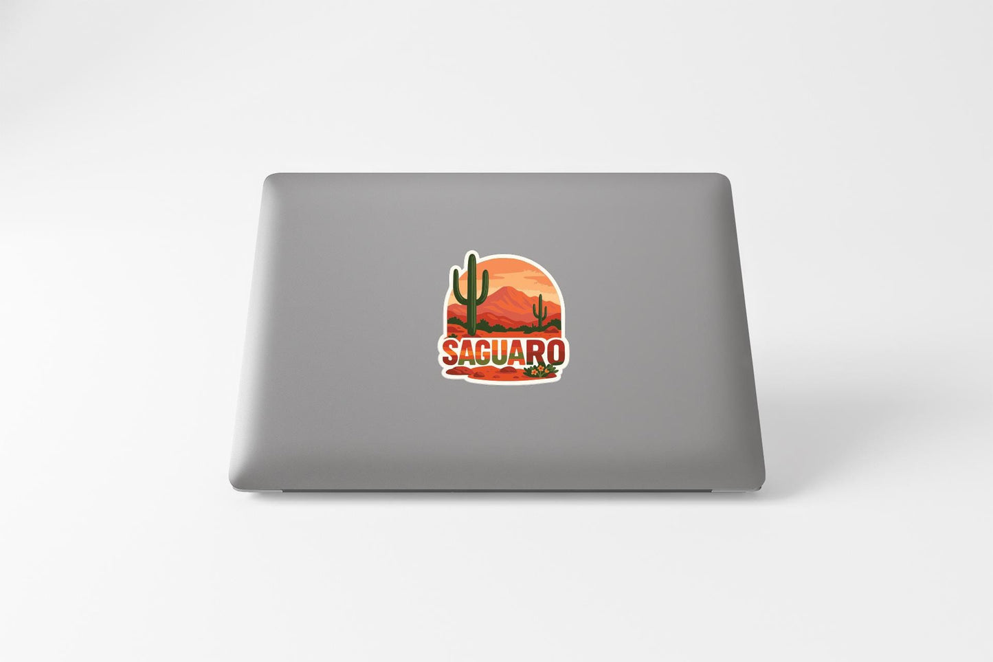 a sticker with a desert landscape and the word "SACUARO" printed on the back of a laptop.