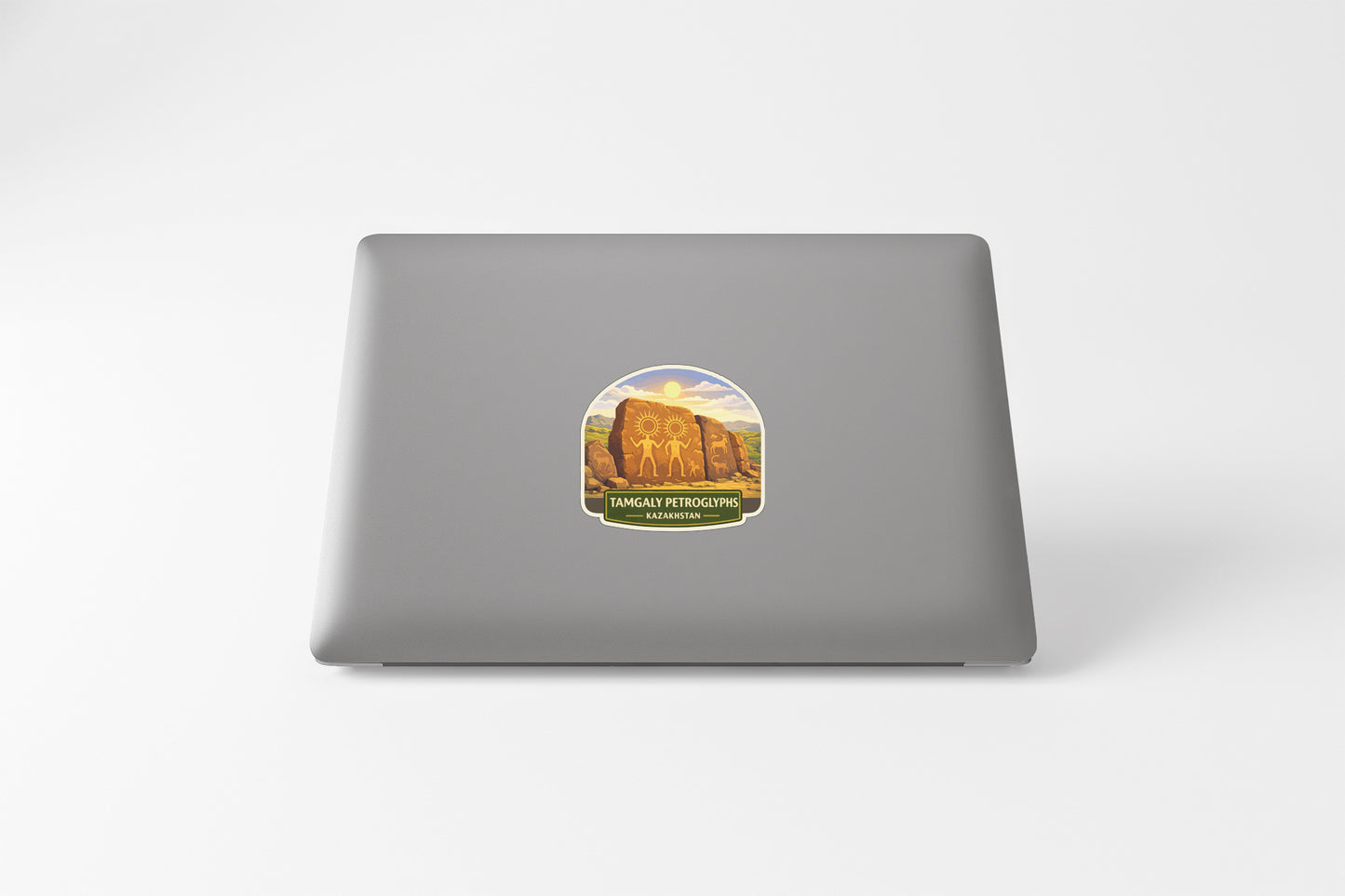 A sticker on the back of a laptop, depicting a scenic landscape with mountains and a river.