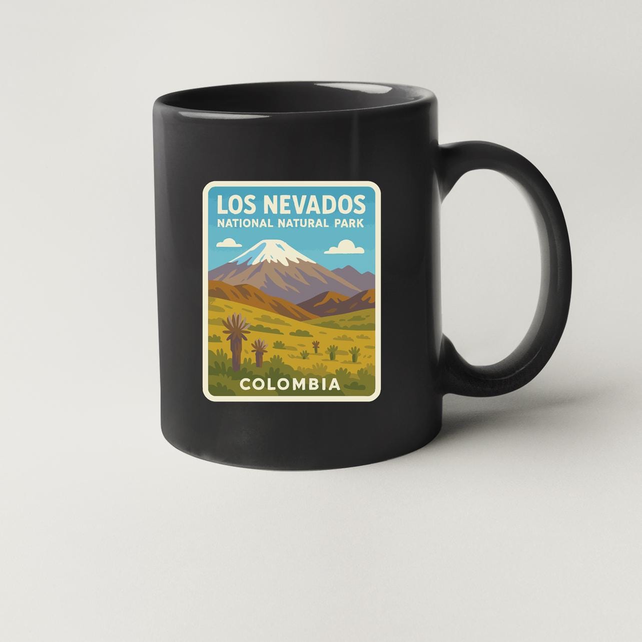 A black coffee mug with a graphic design depicting the Los Nevados National Natural Park in Colombia.