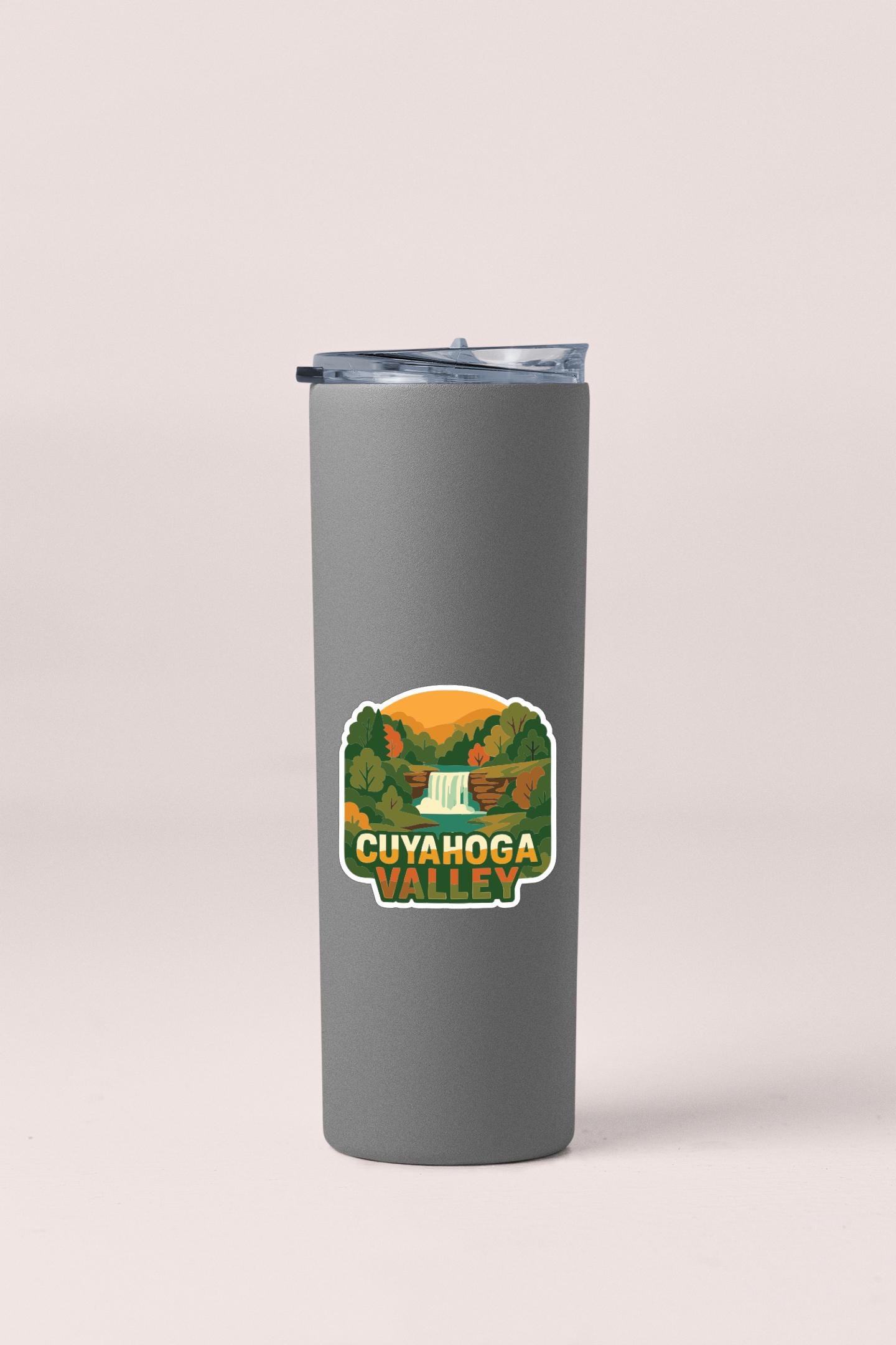 A gray insulated tumbler with a sticker depicting the scenic Cuyahoga Valley.