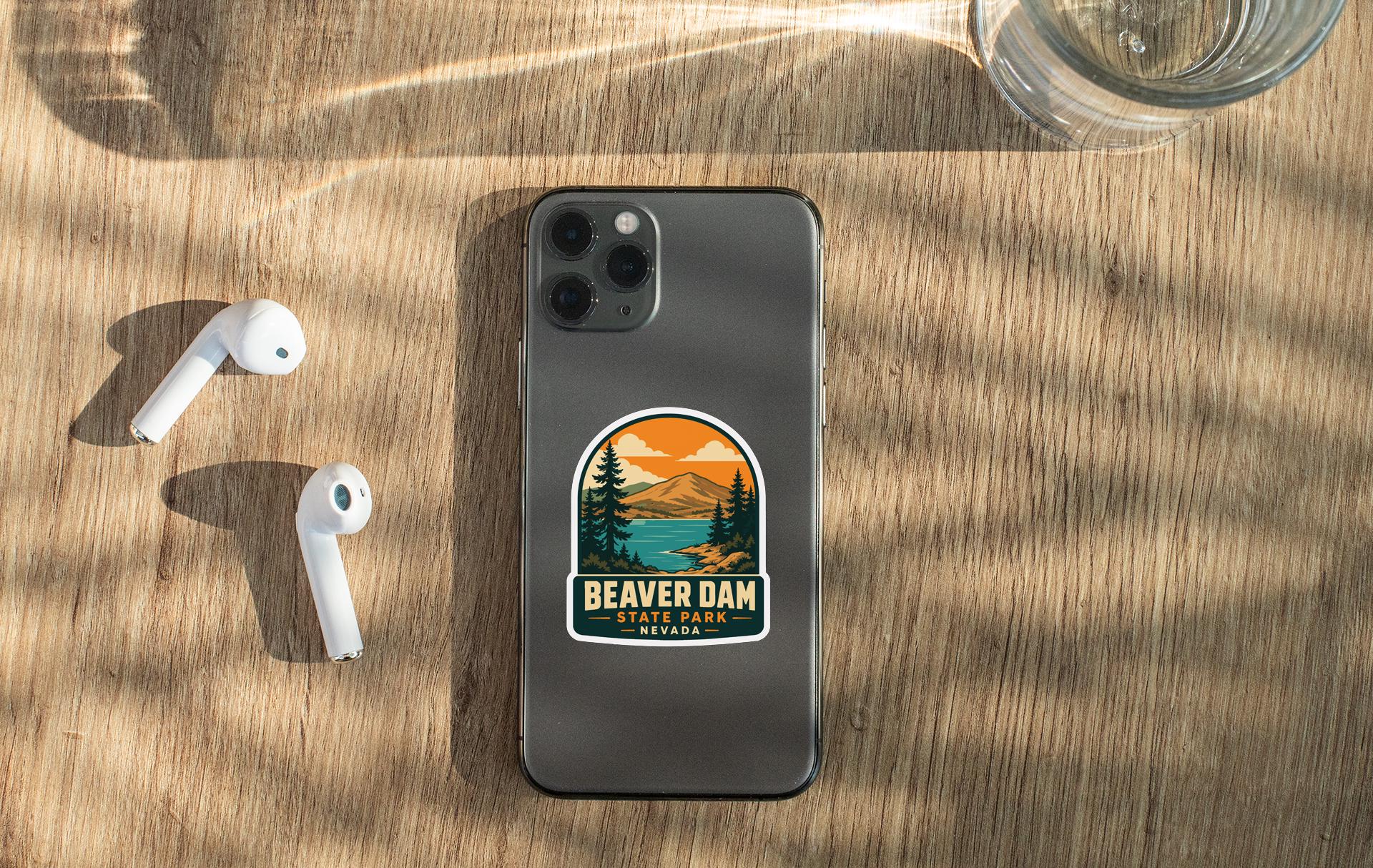 a smartphone with a sticker on the back, placed on a wooden surface alongside a pair of white earbuds and a glass of water.