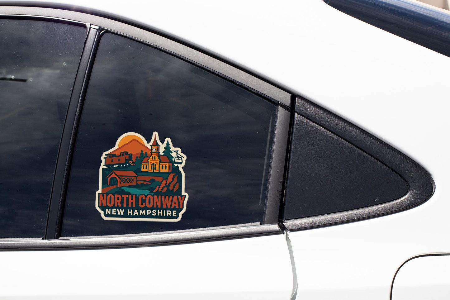 A car window with a sticker depicting a scenic view of North Conway, New Hampshire.