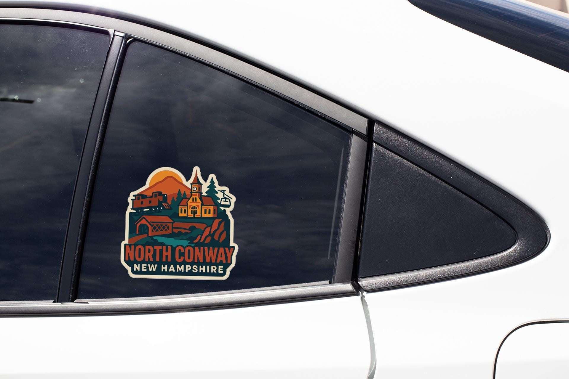 A car window with a sticker depicting a scenic view of North Conway, New Hampshire.